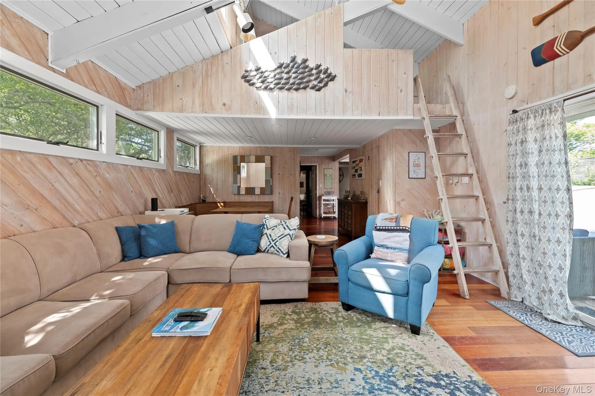 Living area featuring wood walls, wood finished floors, stairs, and wooden ceiling Living area featuring wood walls, wood finished floors, stairs, and wooden ceiling
