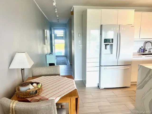 Kitchen featuring stainless steel refrigerator with ice dispenser, rail lighting, modern cabinets, and backsplash Kitchen featuring stainless steel refrigerator with ice dispenser, rail lighting, modern cabinets, and backsplash