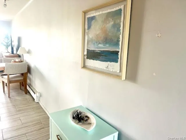 Corridor featuring a baseboard radiator and wood finish floors Corridor featuring a baseboard radiator and wood finish floors