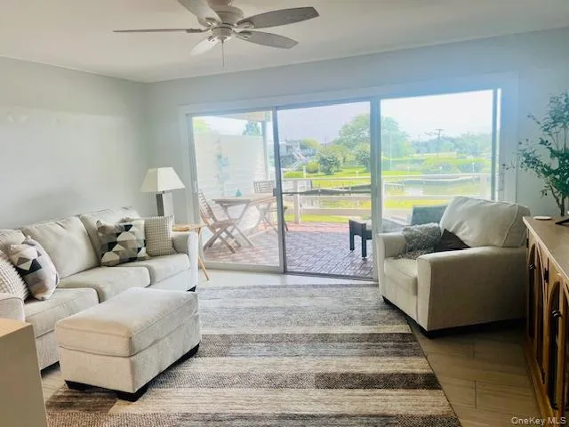 Living room featuring plenty of natural light, light wood-style flooring, and a ceiling fan Living room featuring plenty of natural light, light wood-style flooring, and a ceiling fan