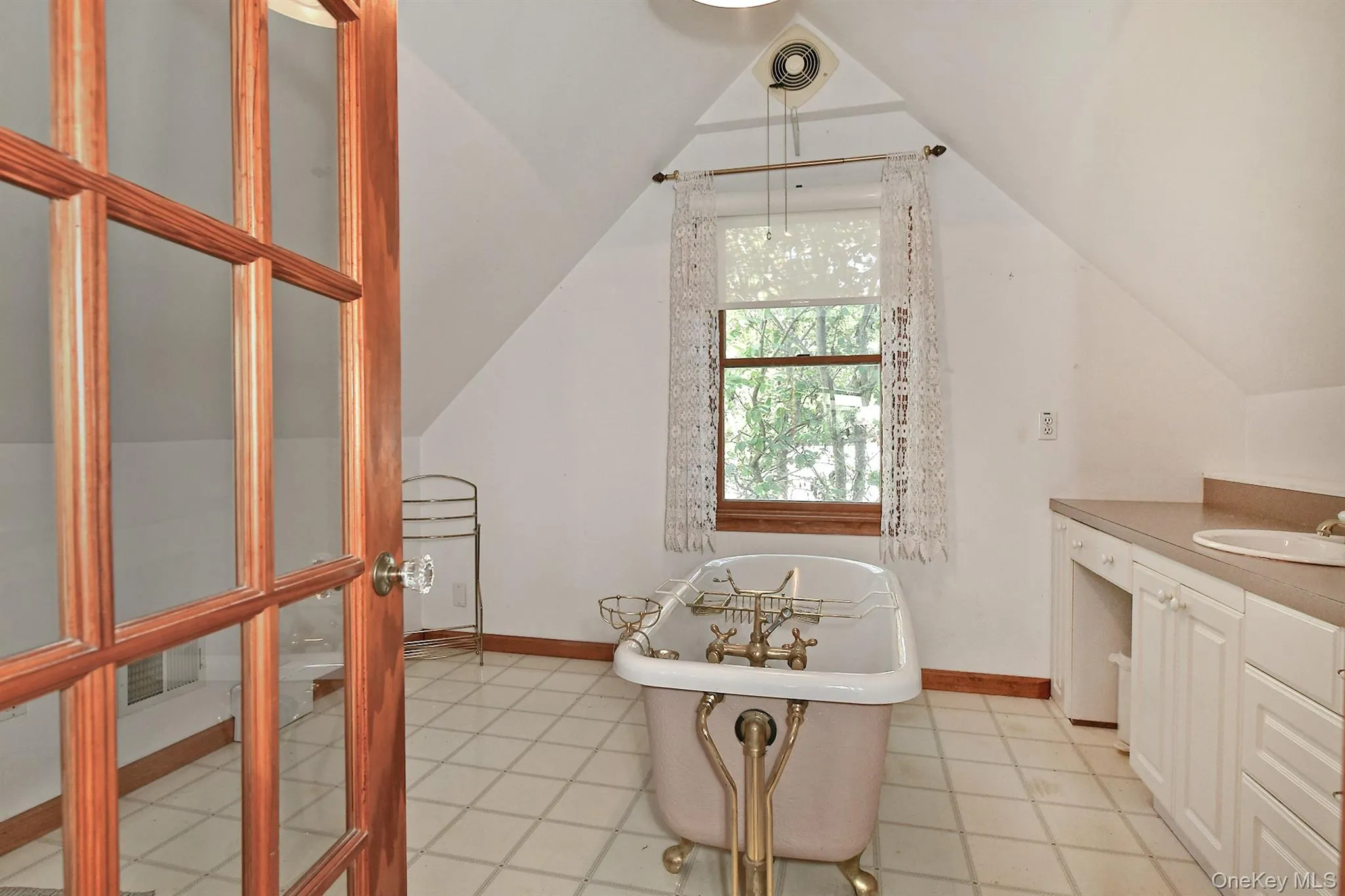 Full bathroom with a soaking tub, vanity, light tile patterned flooring, and lofted ceiling Full bathroom with a soaking tub, vanity, light tile patterned flooring, and lofted ceiling