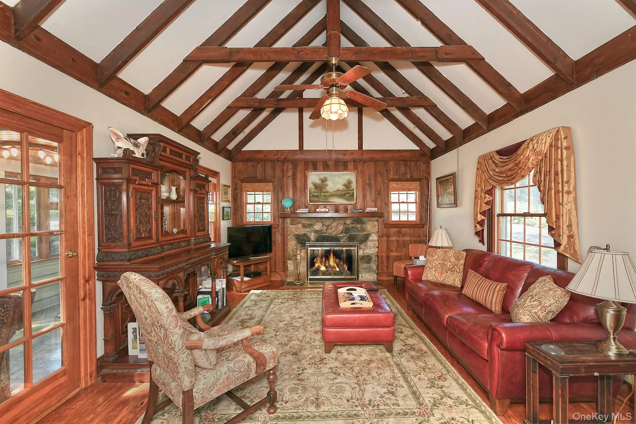 Living area with a stone fireplace, high vaulted ceiling, beamed ceiling, and wood finished floors Living area with a stone fireplace, high vaulted ceiling, beamed ceiling, and wood finished floors