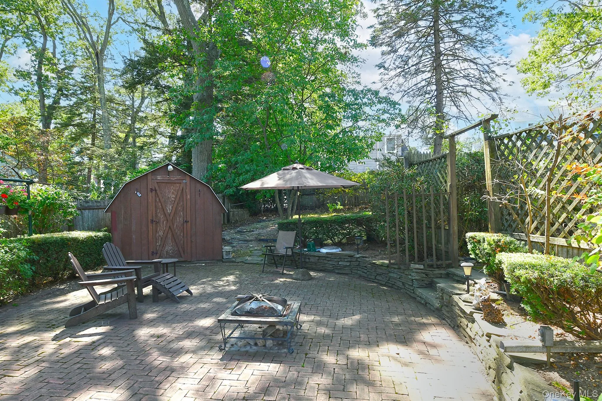 Fenced backyard with a patio area, an outdoor fire pit, and a shed Fenced backyard with a patio area, an outdoor fire pit, and a shed