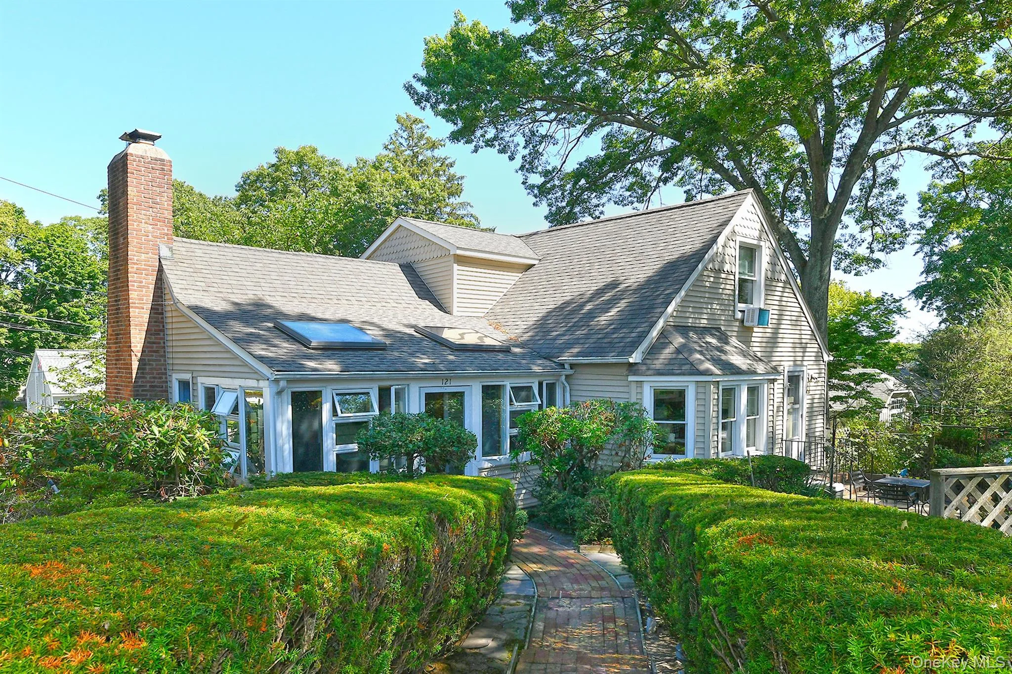 Cape cod-style house featuring a shingled roof and a chimney Cape cod-style house featuring a shingled roof and a chimney