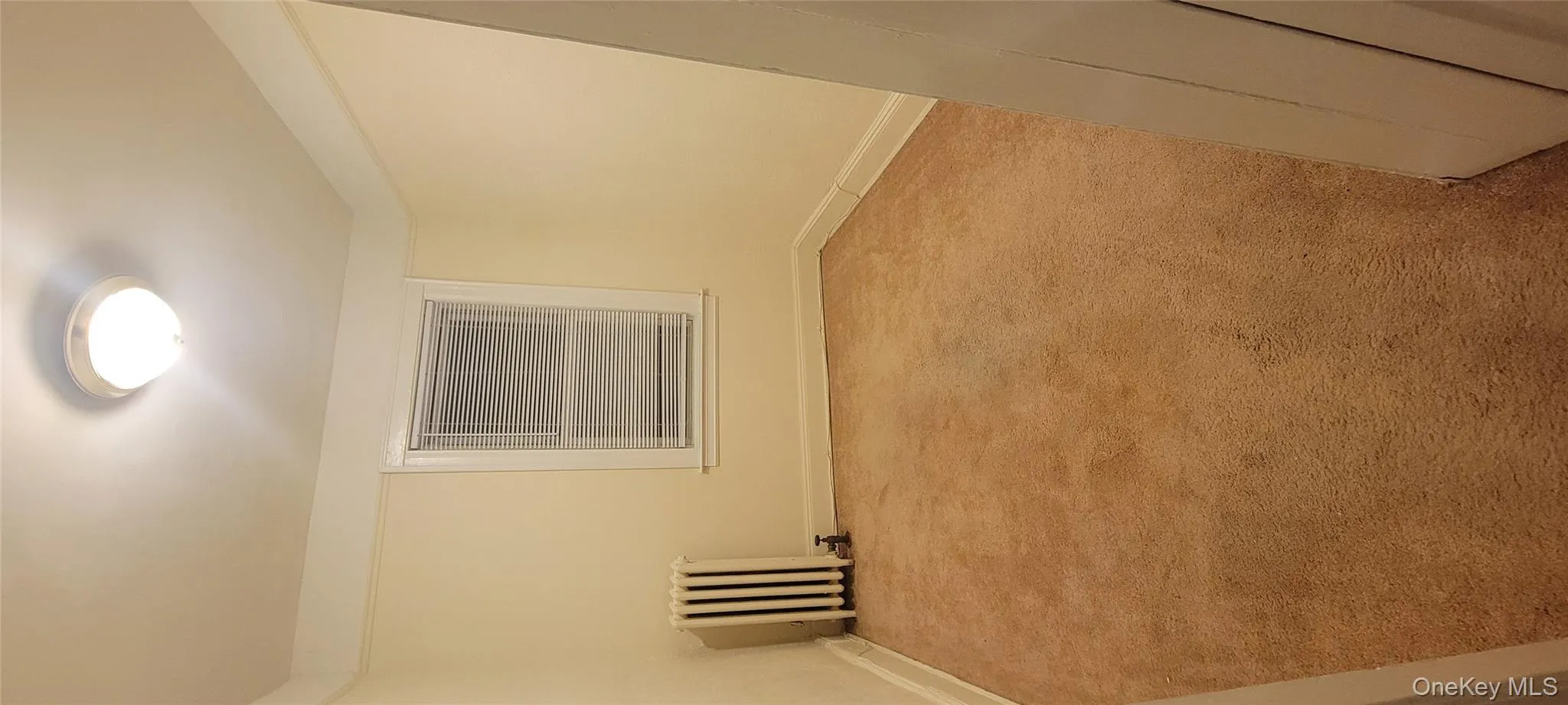 Empty room with light carpet and radiator Empty room with light carpet and radiator