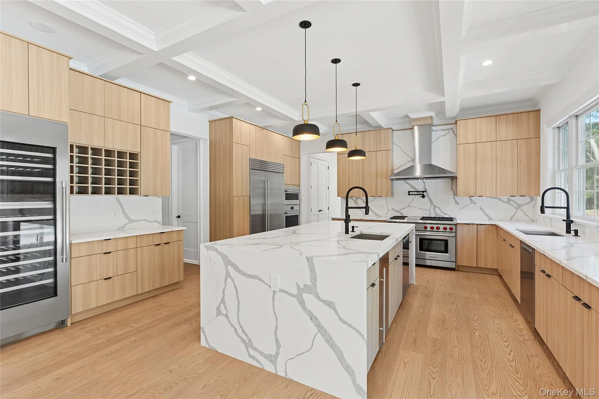 Kitchen featuring light stone counters, hanging light fixtures, modern cabinets, light brown cabinetry, and beamed ceiling Kitchen featuring light stone counters, hanging light fixtures, modern cabinets, light brown cabinetry, and beamed ceiling