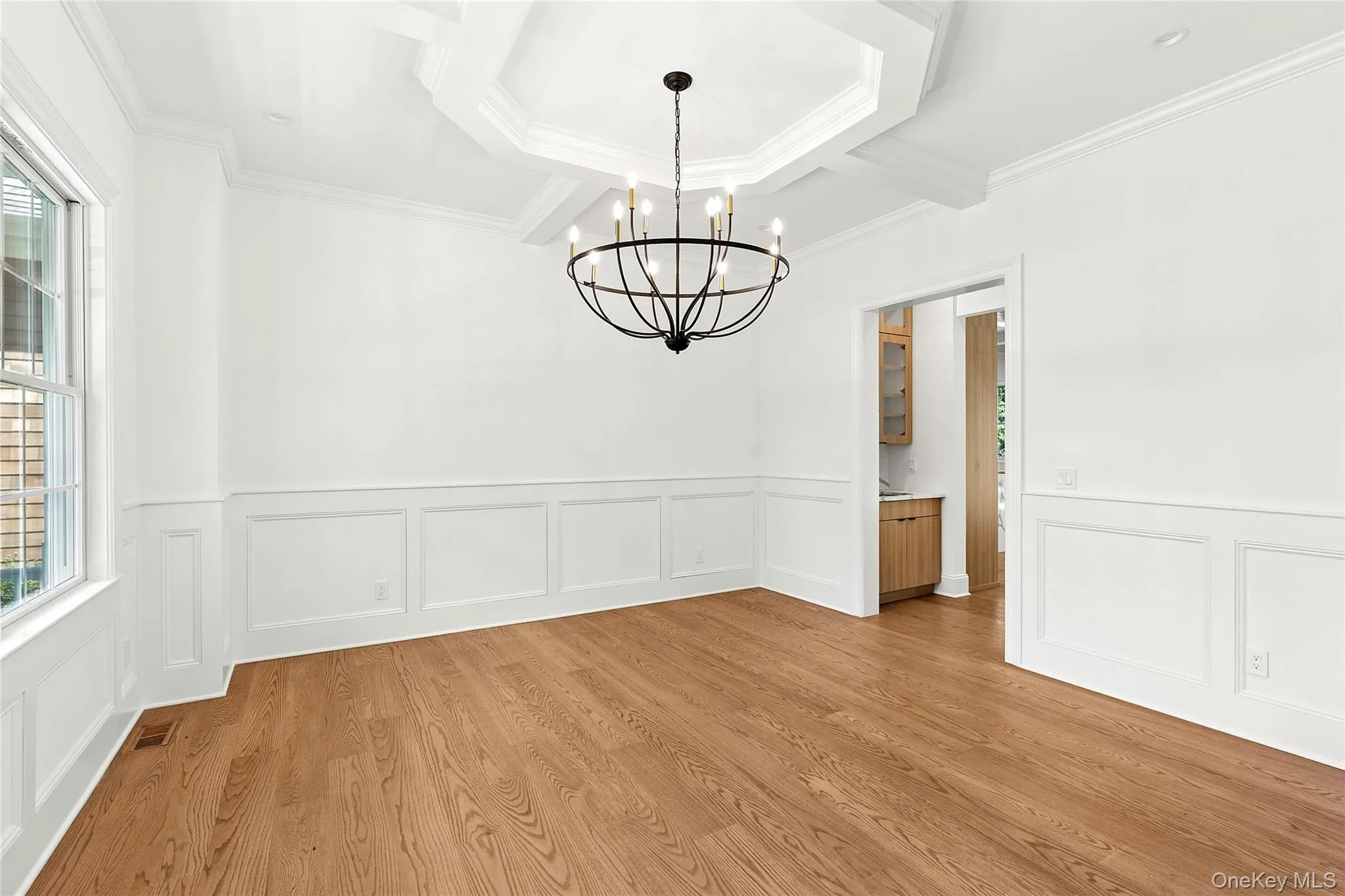 Unfurnished dining area with wood finished floors, coffered ceiling, a wainscoted wall, beam ceiling, and a chandelier Unfurnished dining area with wood finished floors, coffered ceiling, a wainscoted wall, beam ceiling, and a chandelier