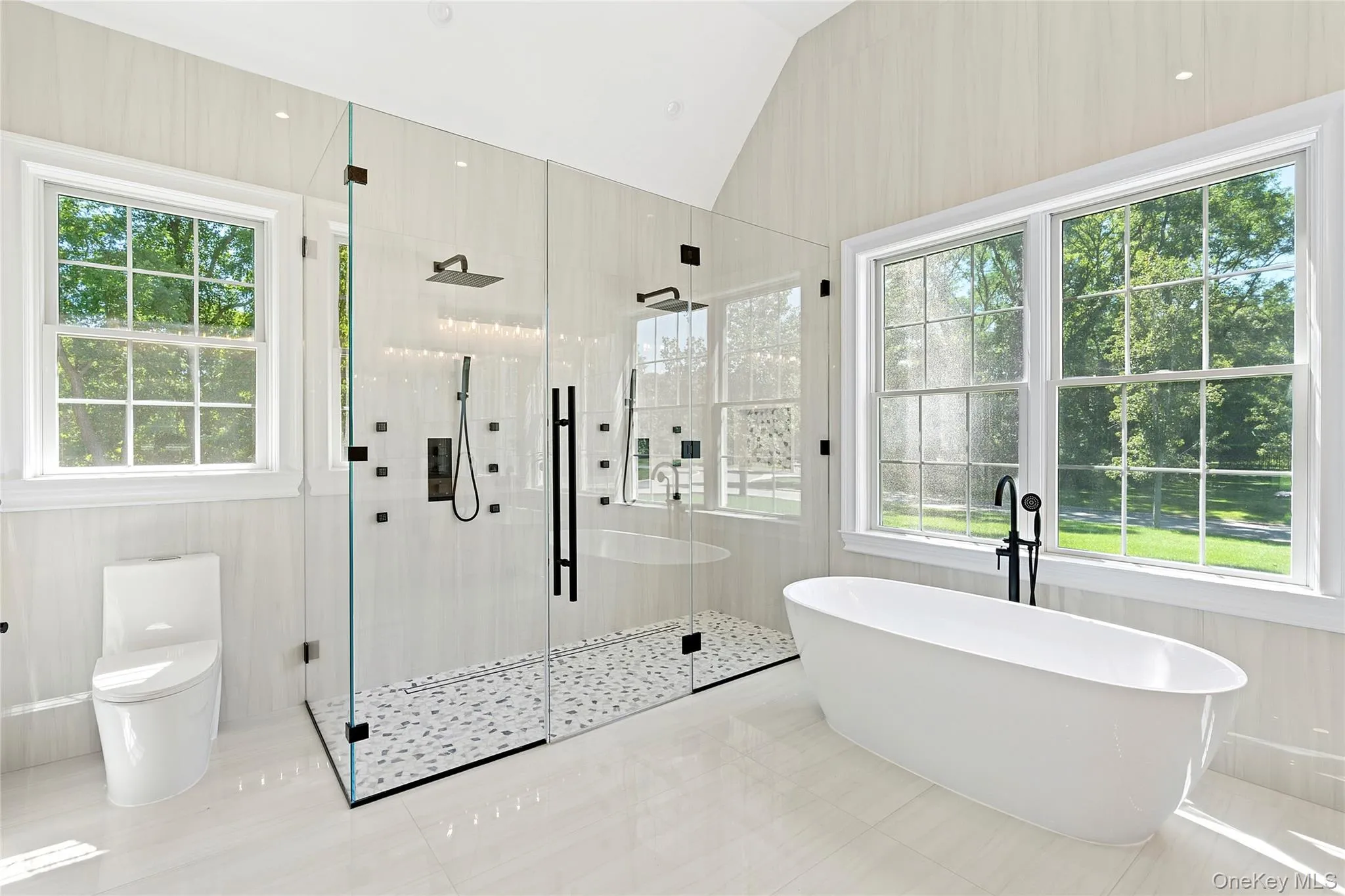 Bathroom with a stall shower, a freestanding tub, lofted ceiling, and tile patterned floors Bathroom with a stall shower, a freestanding tub, lofted ceiling, and tile patterned floors