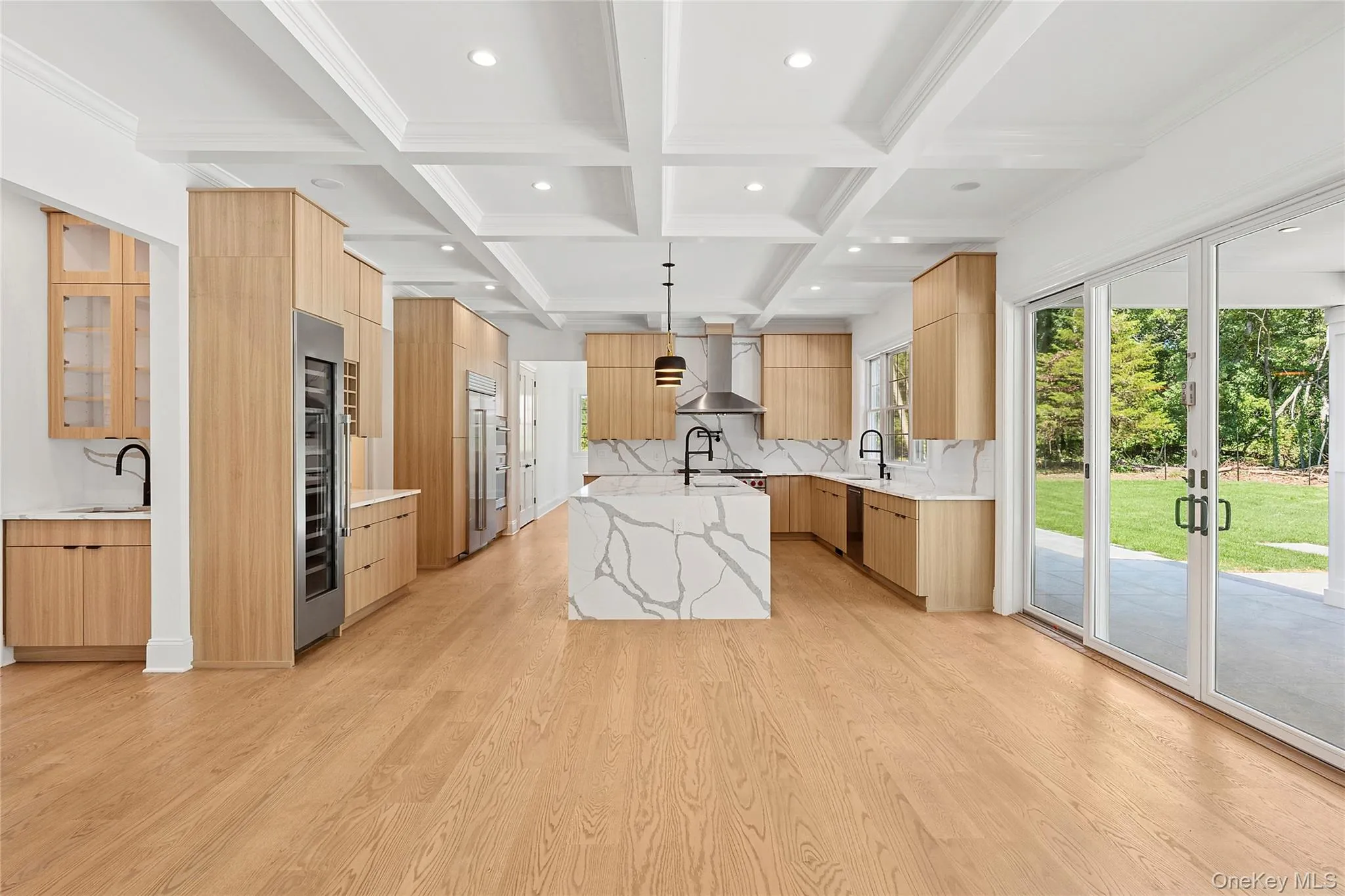 Kitchen with light stone counters, beam ceiling, modern cabinets, coffered ceiling, and light wood-type flooring Kitchen with light stone counters, beam ceiling, modern cabinets, coffered ceiling, and light wood-type flooring