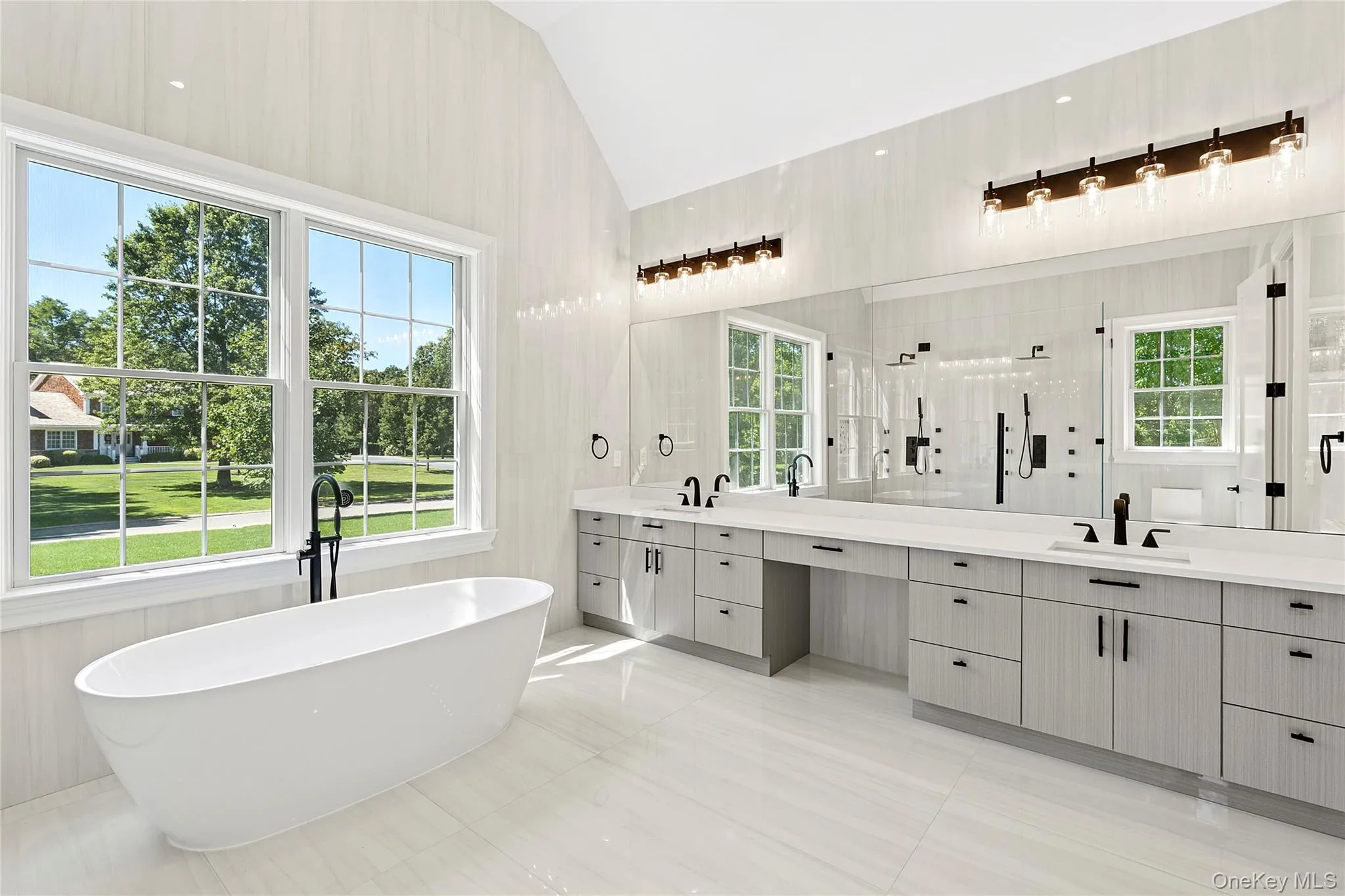 Full bathroom featuring a stall shower, double vanity, a freestanding bath, lofted ceiling, and light tile patterned flooring Full bathroom featuring a stall shower, double vanity, a freestanding bath, lofted ceiling, and light tile patterned flooring