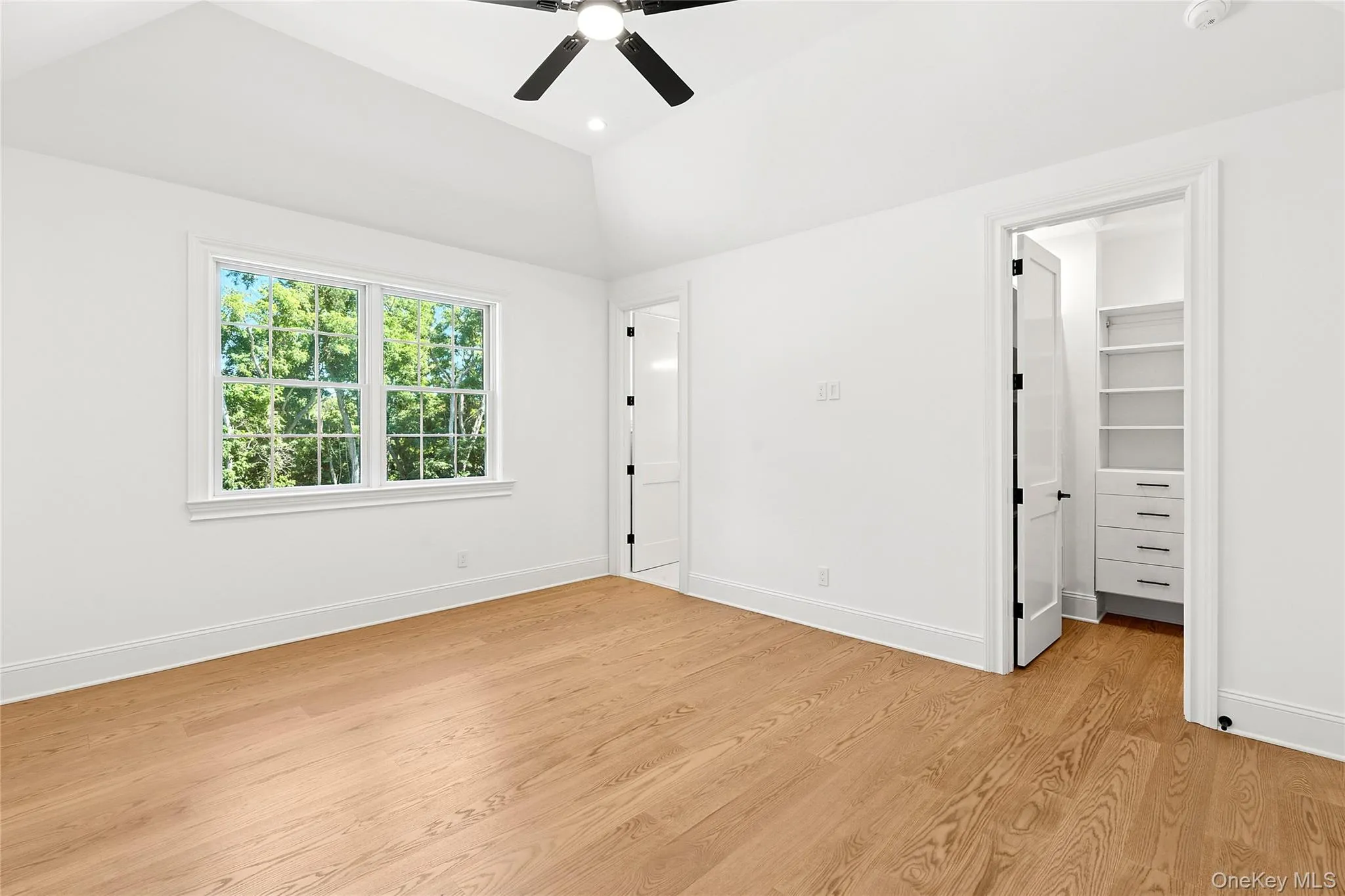 Unfurnished bedroom featuring a walk in closet, light wood finished floors, ceiling fan, recessed lighting, and lofted ceiling Unfurnished bedroom featuring a walk in closet, light wood finished floors, ceiling fan, recessed lighting, and lofted ceiling
