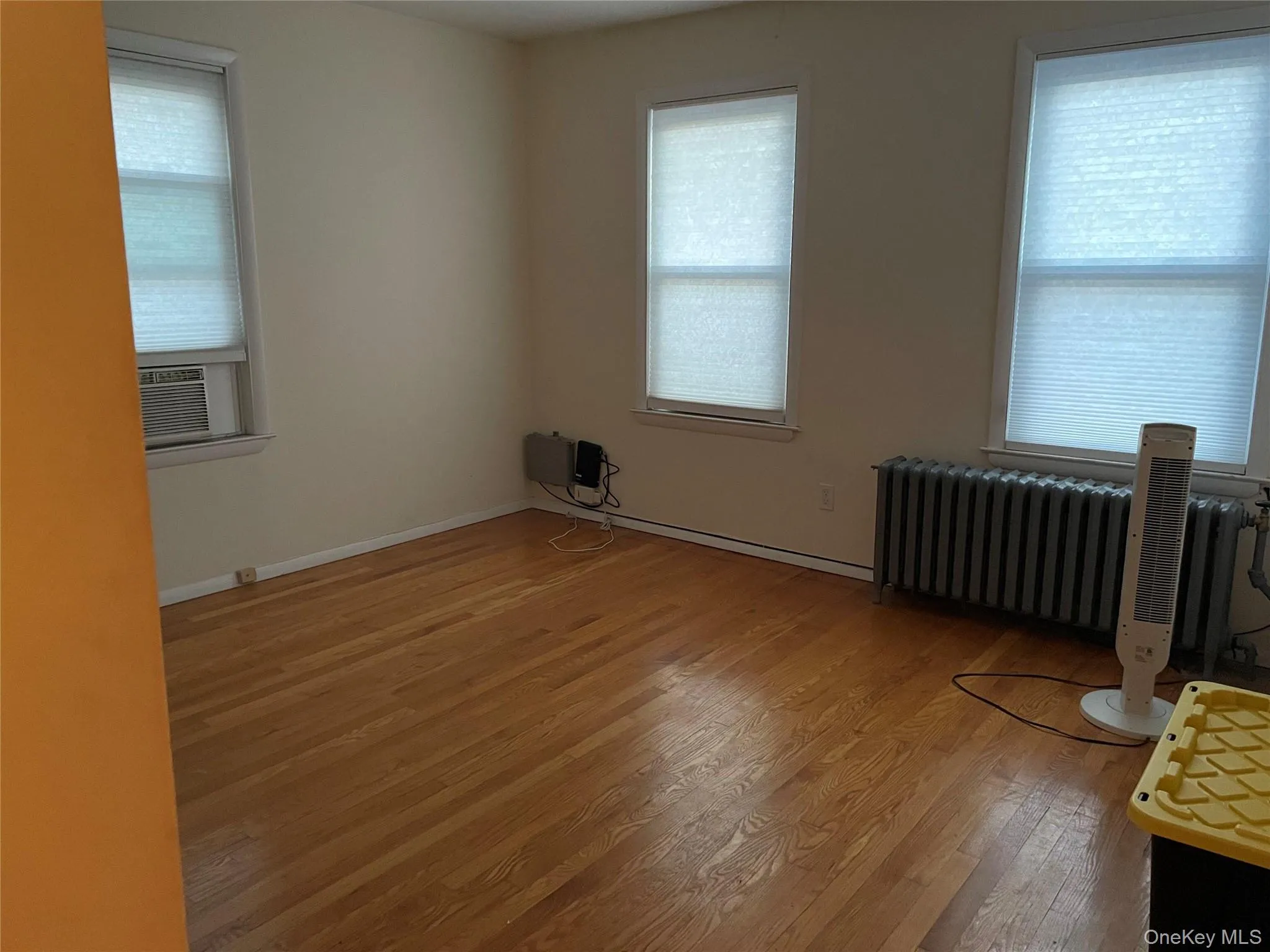 Spare room with radiator heating unit, light wood-style flooring, and cooling unit Spare room with radiator heating unit, light wood-style flooring, and cooling unit