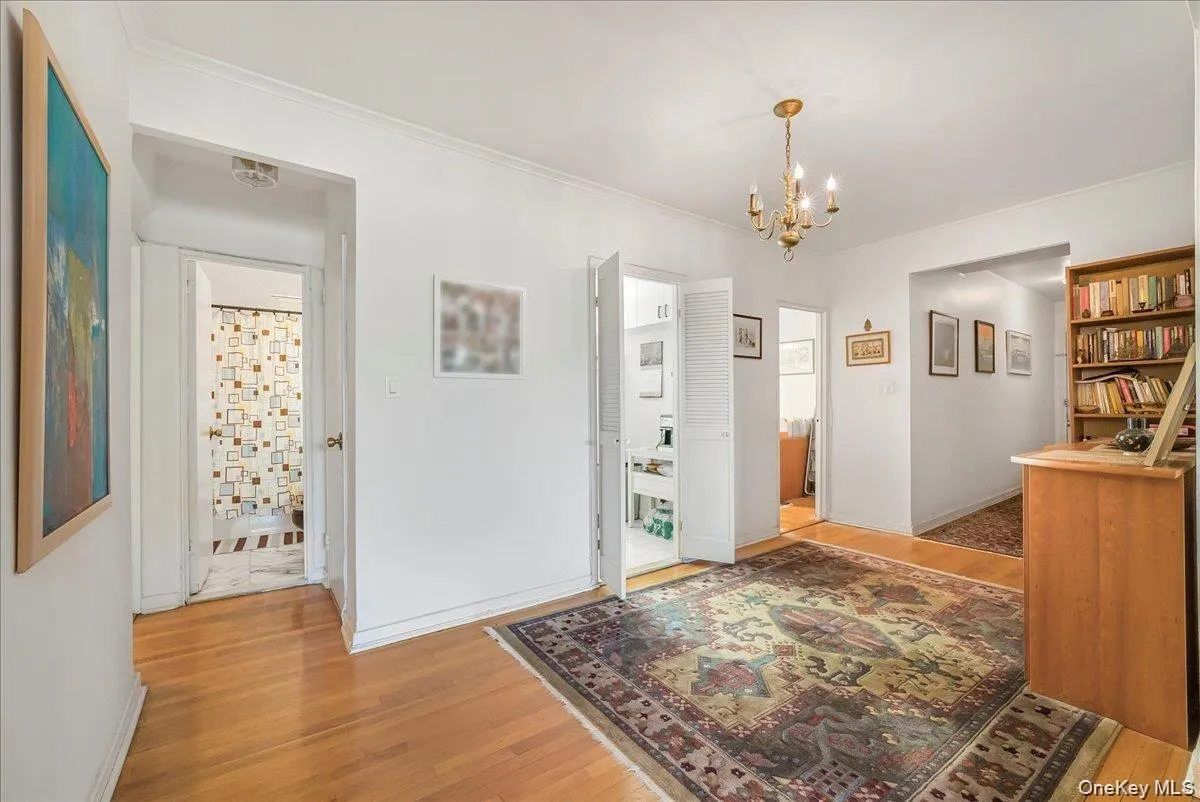 Hallway with light wood-style flooring and a chandelier Hallway with light wood-style flooring and a chandelier