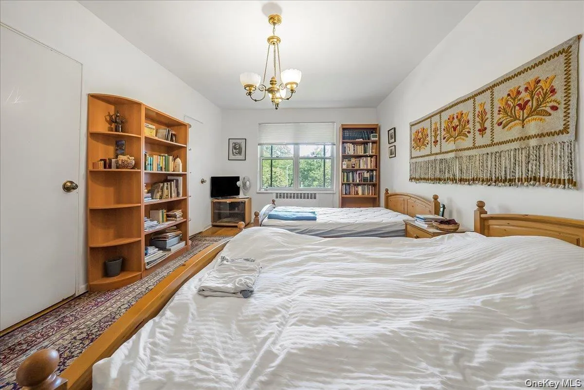Bedroom with a chandelier, wood finished floors, and radiator Bedroom with a chandelier, wood finished floors, and radiator