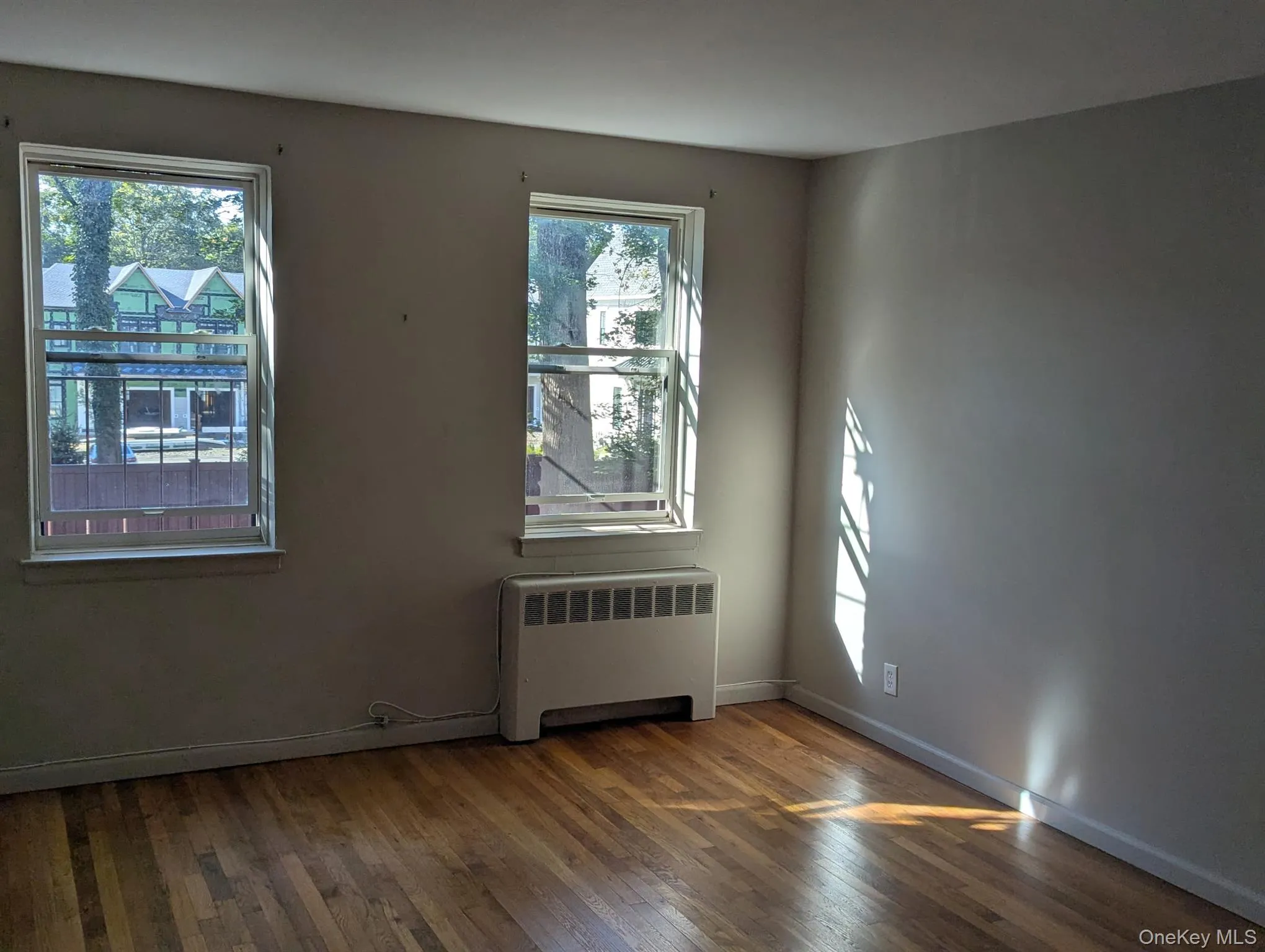 Empty room with radiator and dark wood-style floors Empty room with radiator and dark wood-style floors