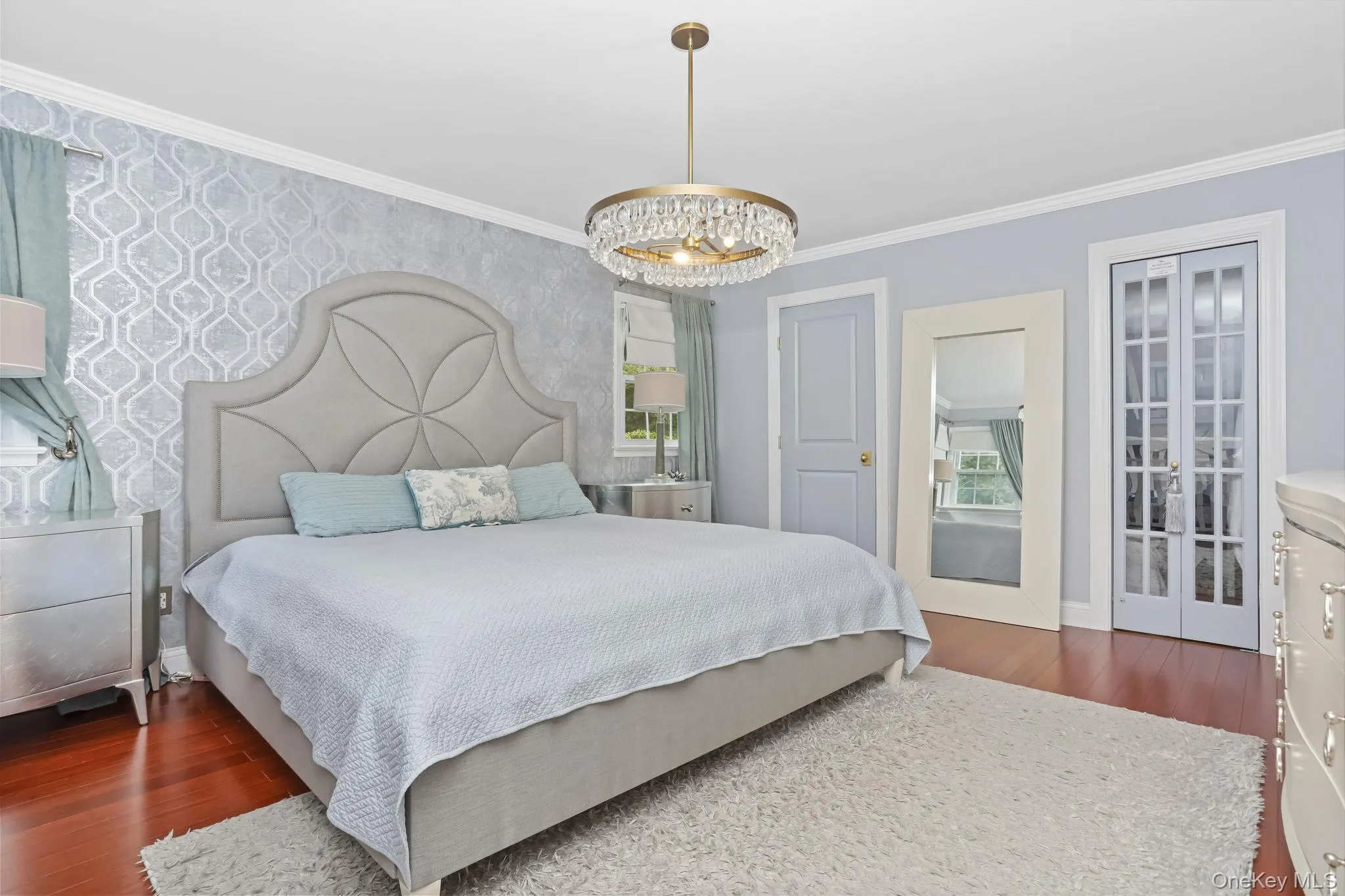 Primary bedroom featuring crown molding, dark wood-style floors, and a chandelier Primary bedroom featuring crown molding, dark wood-style floors, and a chandelier