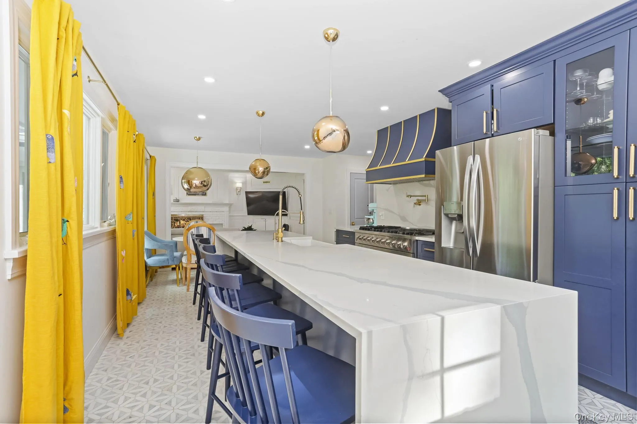 Kitchen with blue cabinets, a kitchen breakfast bar, glass insert cabinets, hanging light fixtures, and stainless steel refrigerator with ice dispenser Kitchen with blue cabinets, a kitchen breakfast bar, glass insert cabinets, hanging light fixtures, and stainless steel refrigerator with ice dispenser