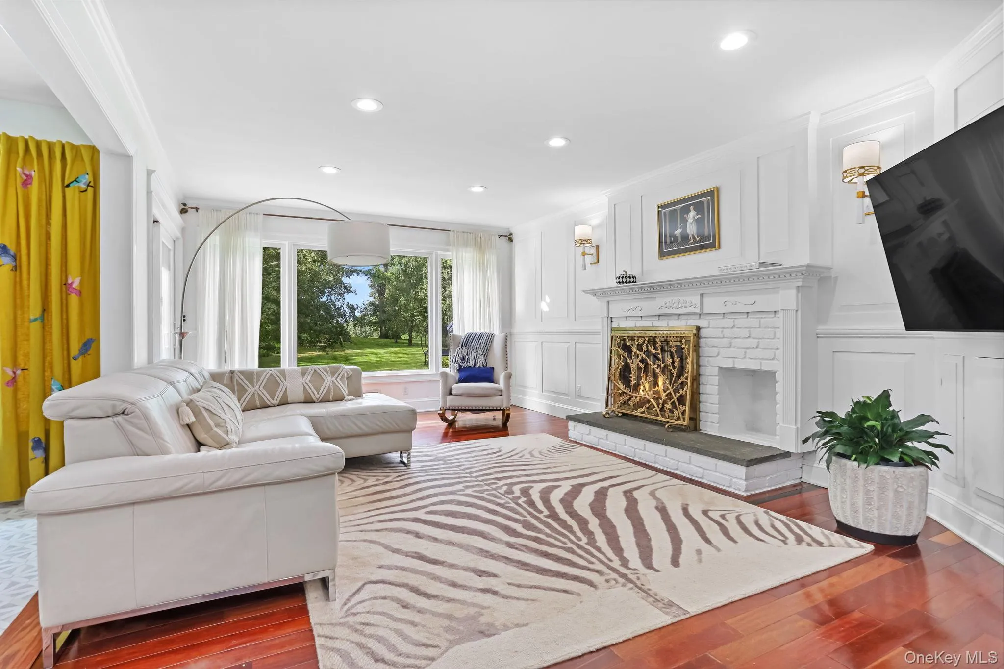 Living area featuring a decorative wall, dark wood-type flooring, recessed lighting, a brick fireplace, and ornamental molding Living area featuring a decorative wall, dark wood-type flooring, recessed lighting, a brick fireplace, and ornamental molding