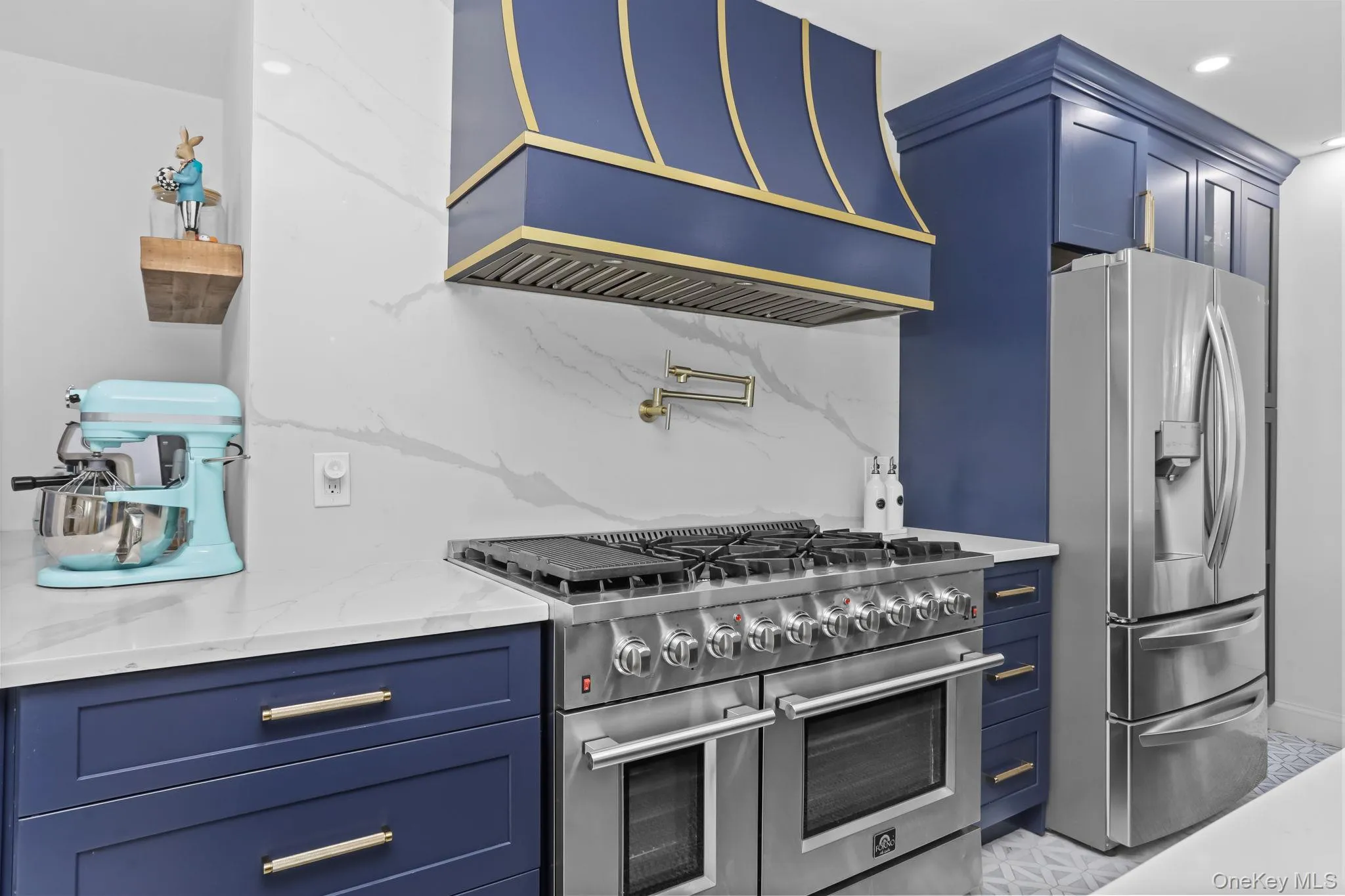 Kitchen with blue cabinets, premium range hood, appliances with stainless steel finishes, backsplash, and recessed lighting Kitchen with blue cabinets, premium range hood, appliances with stainless steel finishes, backsplash, and recessed lighting