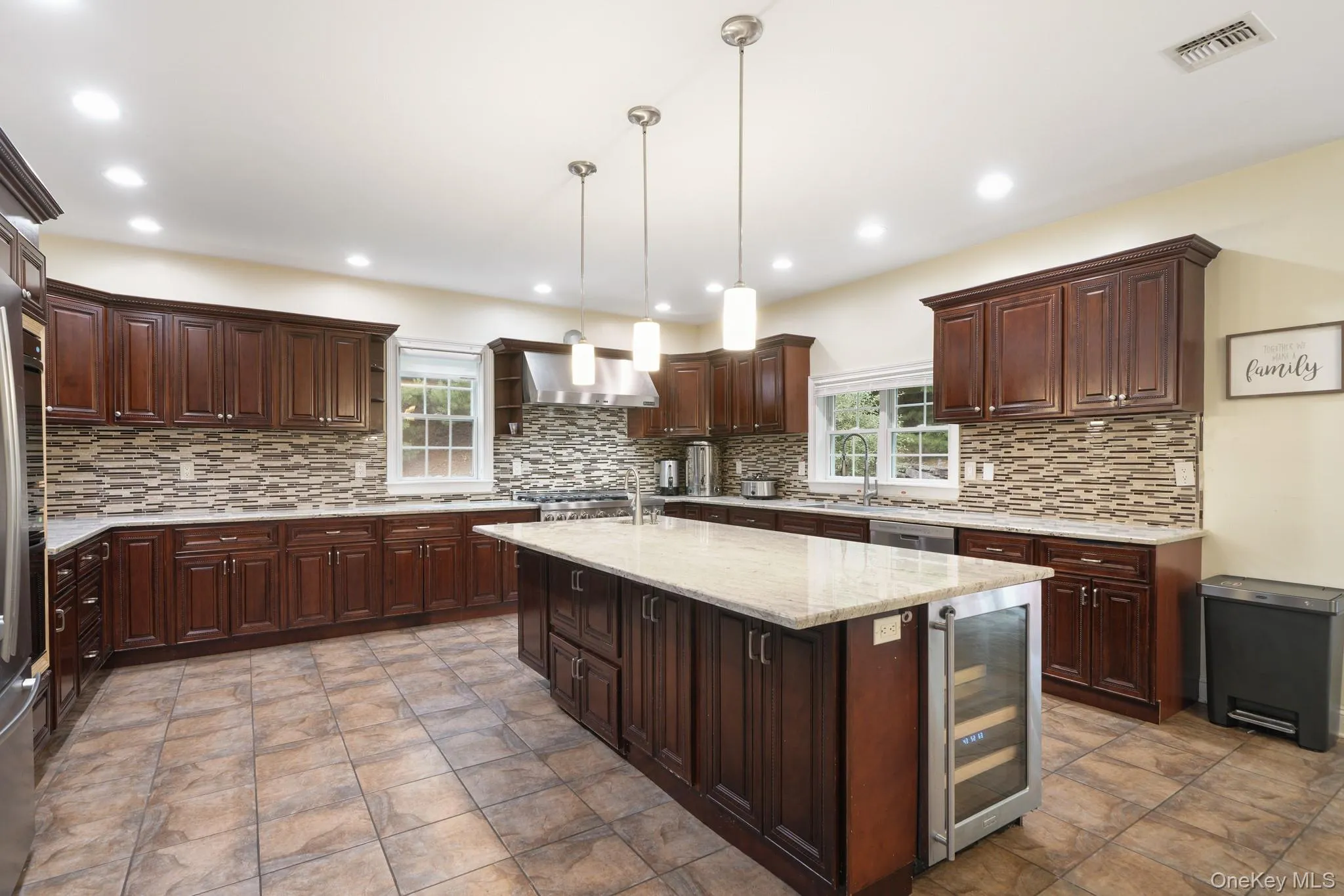 Kitchen with decorative backsplash, dark brown cabinets, wine cooler, and recessed lighting Kitchen with decorative backsplash, dark brown cabinets, wine cooler, and recessed lighting