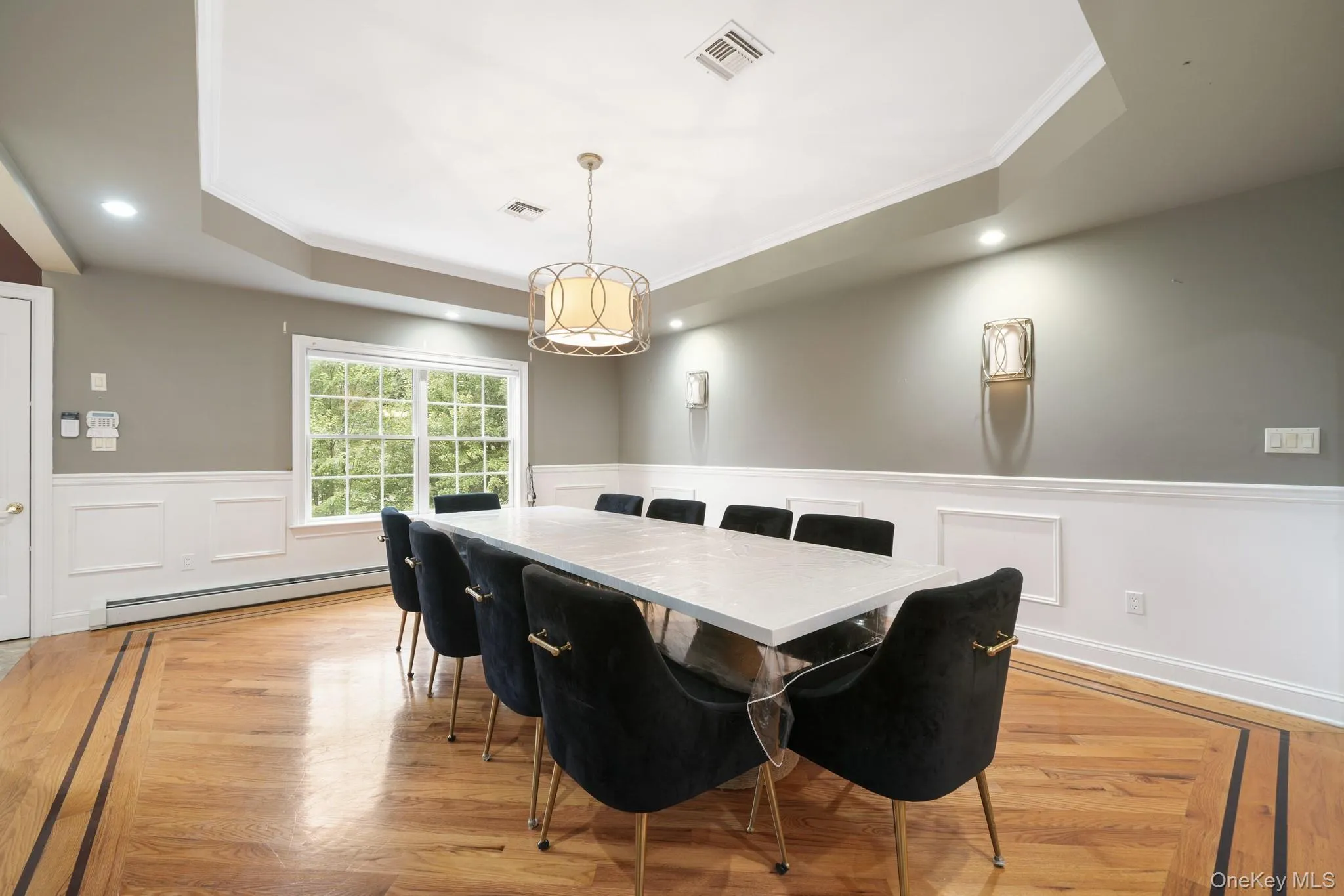 Dining area featuring a raised ceiling, a baseboard heating unit, light wood-style floors, recessed lighting, and crown molding Dining area featuring a raised ceiling, a baseboard heating unit, light wood-style floors, recessed lighting, and crown molding