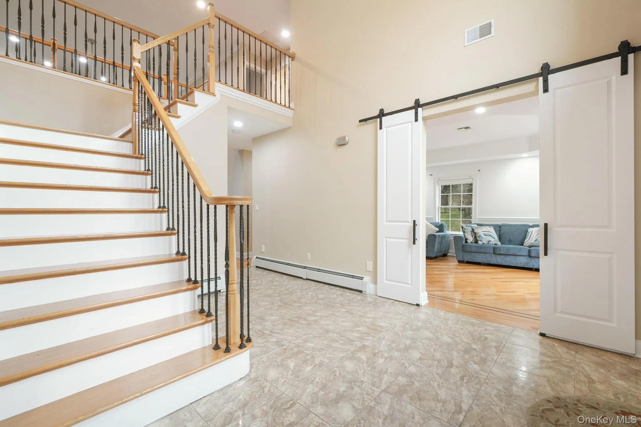 Stairs with a baseboard radiator, recessed lighting, a barn door, a towering ceiling, and tile patterned flooring Stairs with a baseboard radiator, recessed lighting, a barn door, a towering ceiling, and tile patterned flooring