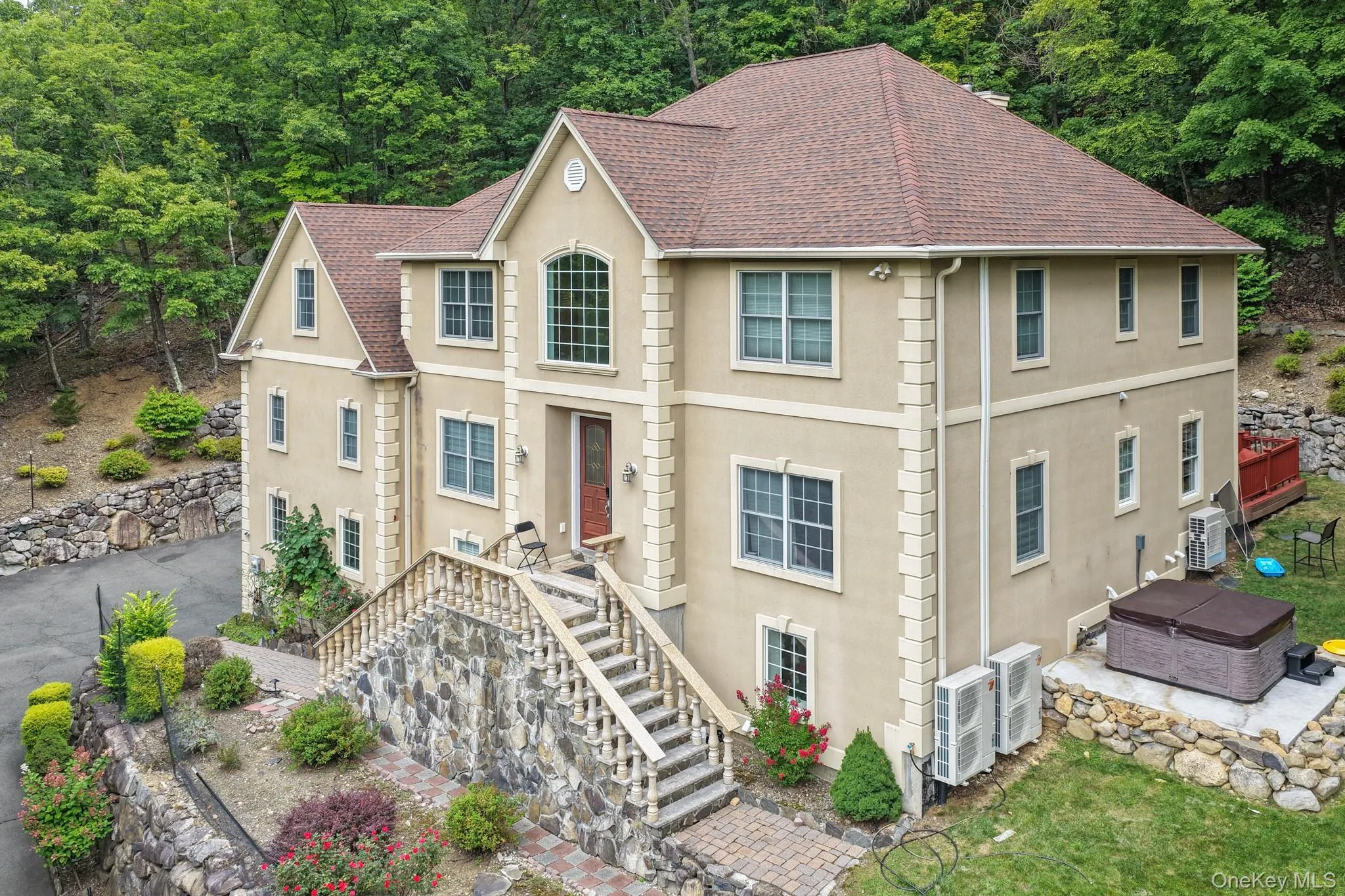 Traditional-style house with stucco siding, stairs, roof with shingles, and a hot tub Traditional-style house with stucco siding, stairs, roof with shingles, and a hot tub