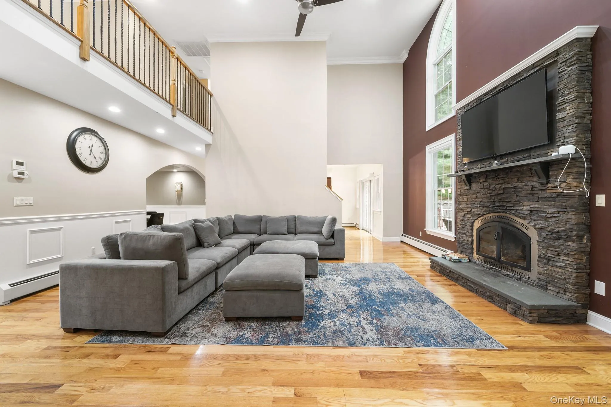 Living room with a fireplace, light wood finished floors, crown molding, baseboard heating, and recessed lighting Living room with a fireplace, light wood finished floors, crown molding, baseboard heating, and recessed lighting