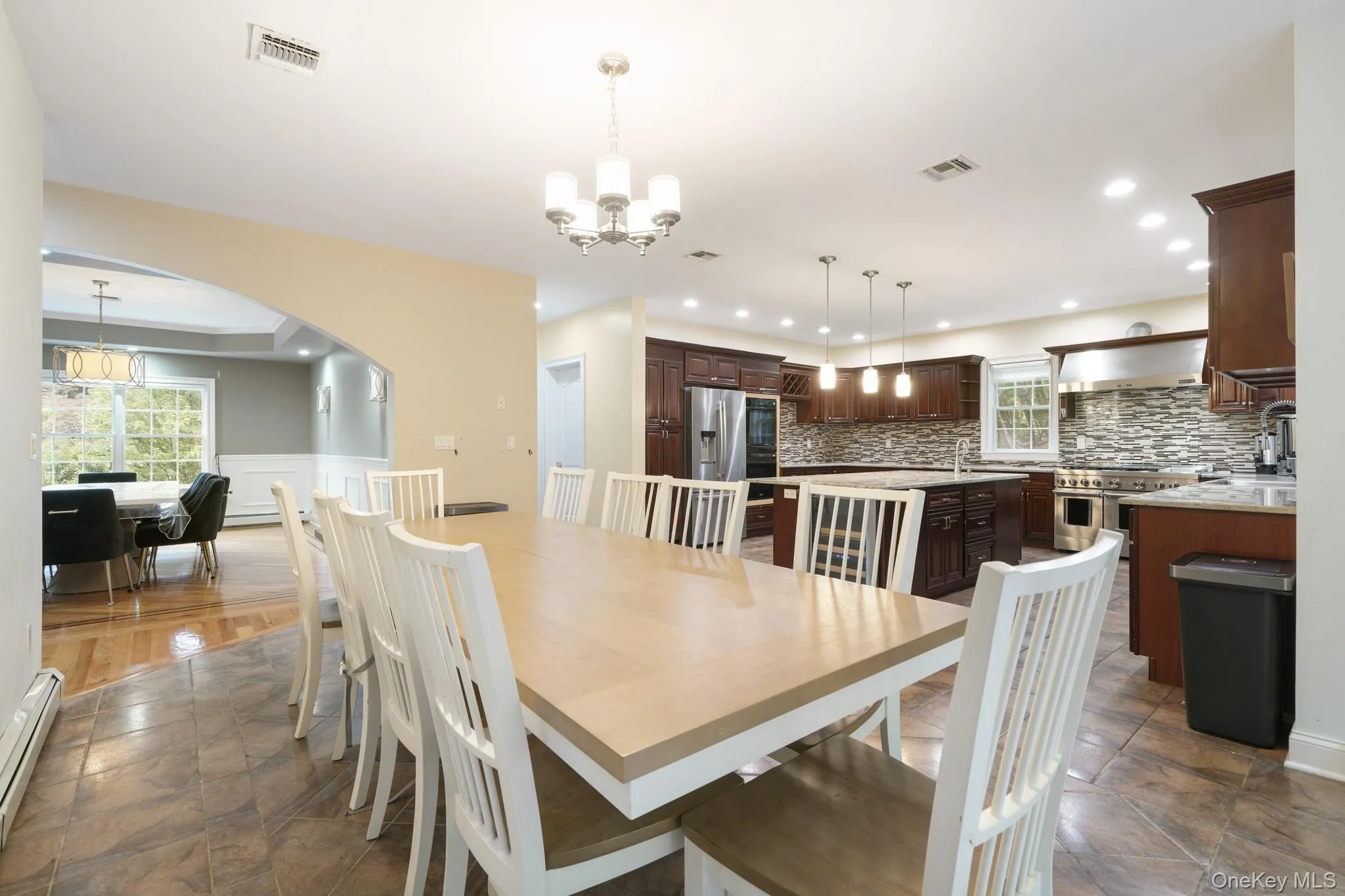 Dining space featuring a chandelier, arched walkways, and a baseboard heating unit Dining space featuring a chandelier, arched walkways, and a baseboard heating unit