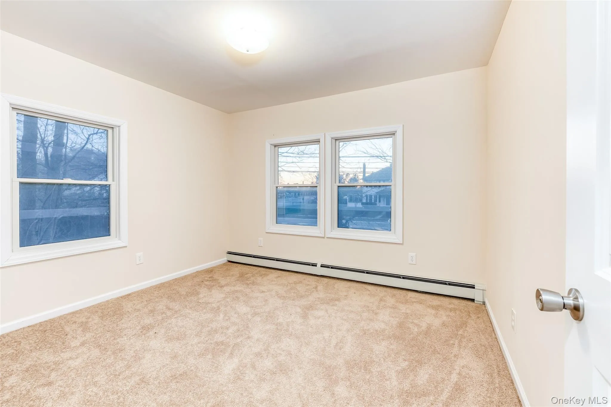 Empty room featuring carpet floors and a baseboard heating unit Empty room featuring carpet floors and a baseboard heating unit
