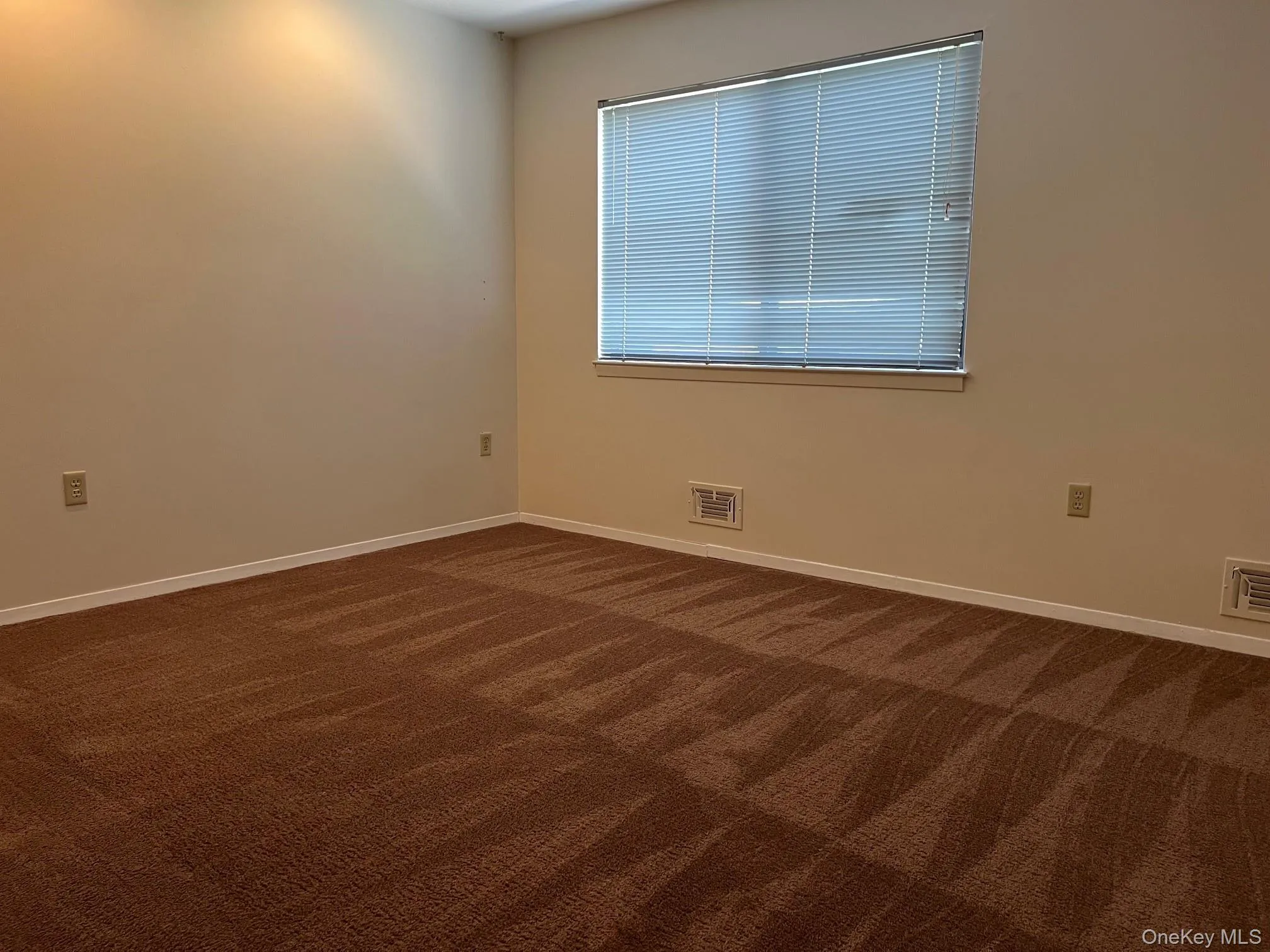 Unfurnished room featuring dark colored carpet and baseboards Unfurnished room featuring dark colored carpet and baseboards