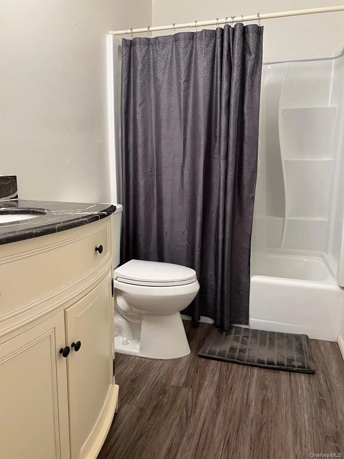 Bathroom featuring shower / bath combo, vanity, and dark wood-style flooring Bathroom featuring shower / bath combo, vanity, and dark wood-style flooring