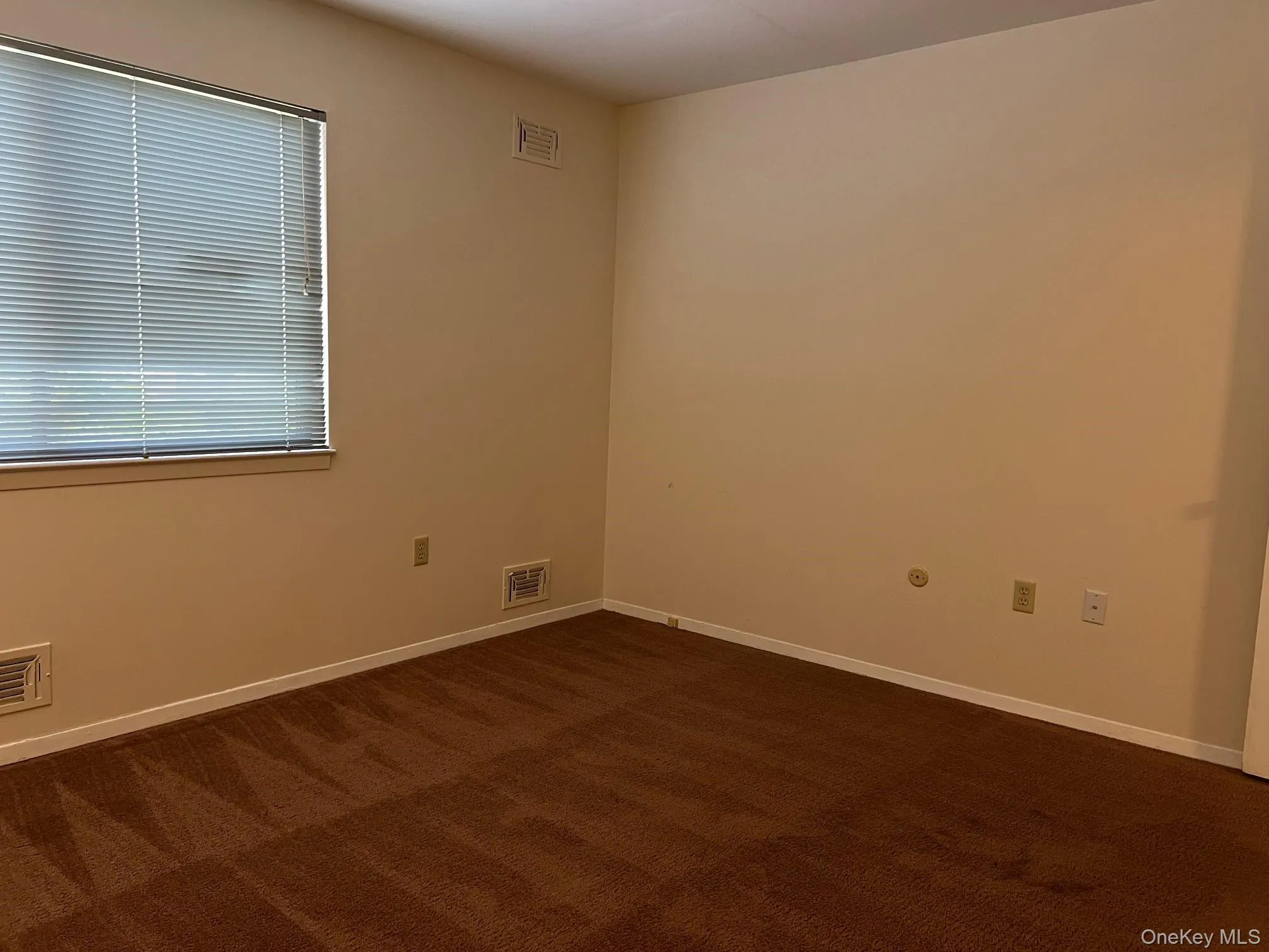 Unfurnished room with dark carpet and baseboards Unfurnished room with dark carpet and baseboards
