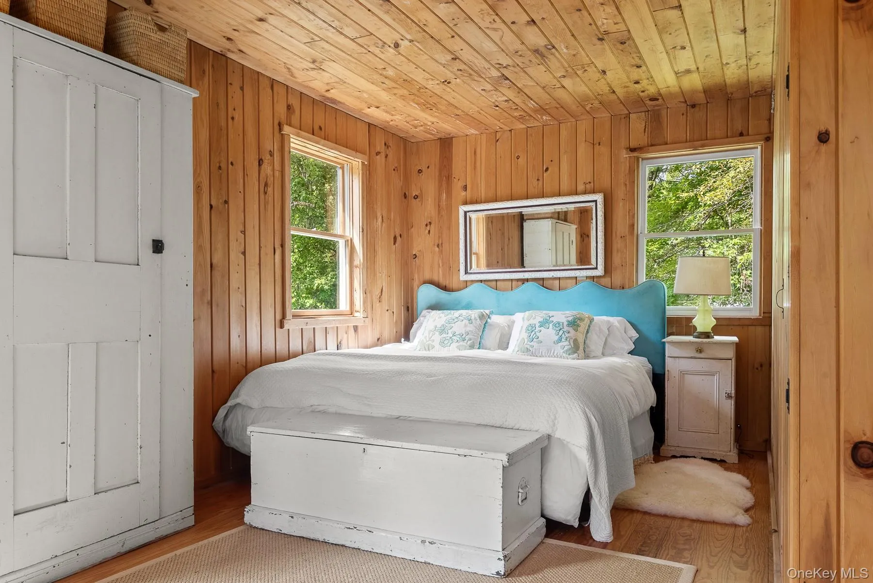 Bedroom with wood finished floors, wood ceiling, multiple windows, and wooden walls Bedroom with wood finished floors, wood ceiling, multiple windows, and wooden walls