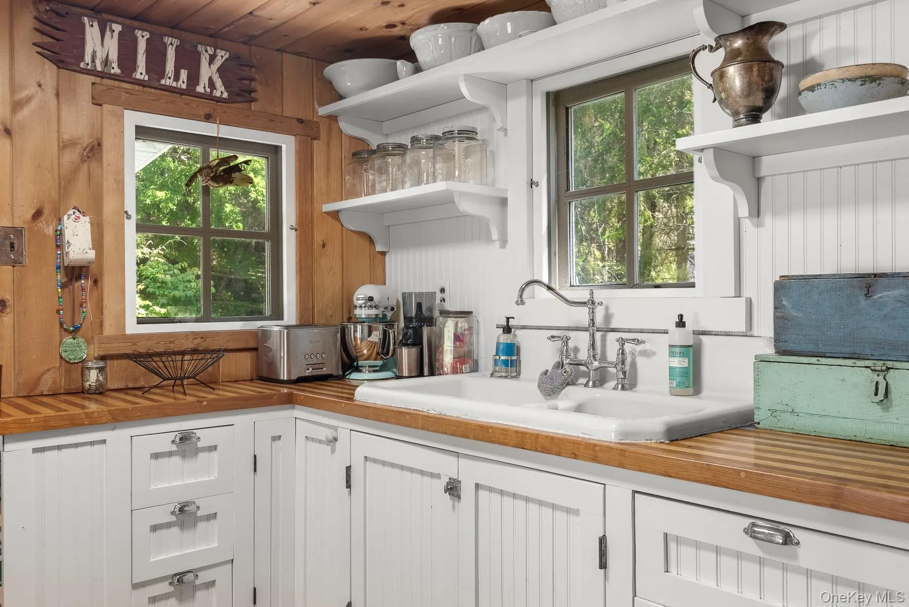 Kitchen featuring butcher block counters, open shelves, white cabinetry, and wood walls Kitchen featuring butcher block counters, open shelves, white cabinetry, and wood walls