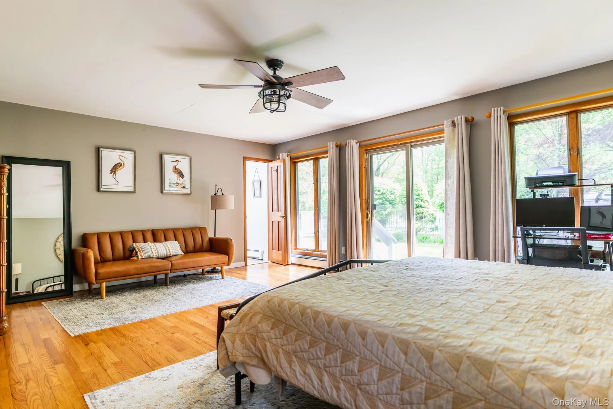 Bedroom featuring access to outside, wood finished floors, ceiling fan, and baseboard heating Bedroom featuring access to outside, wood finished floors, ceiling fan, and baseboard heating