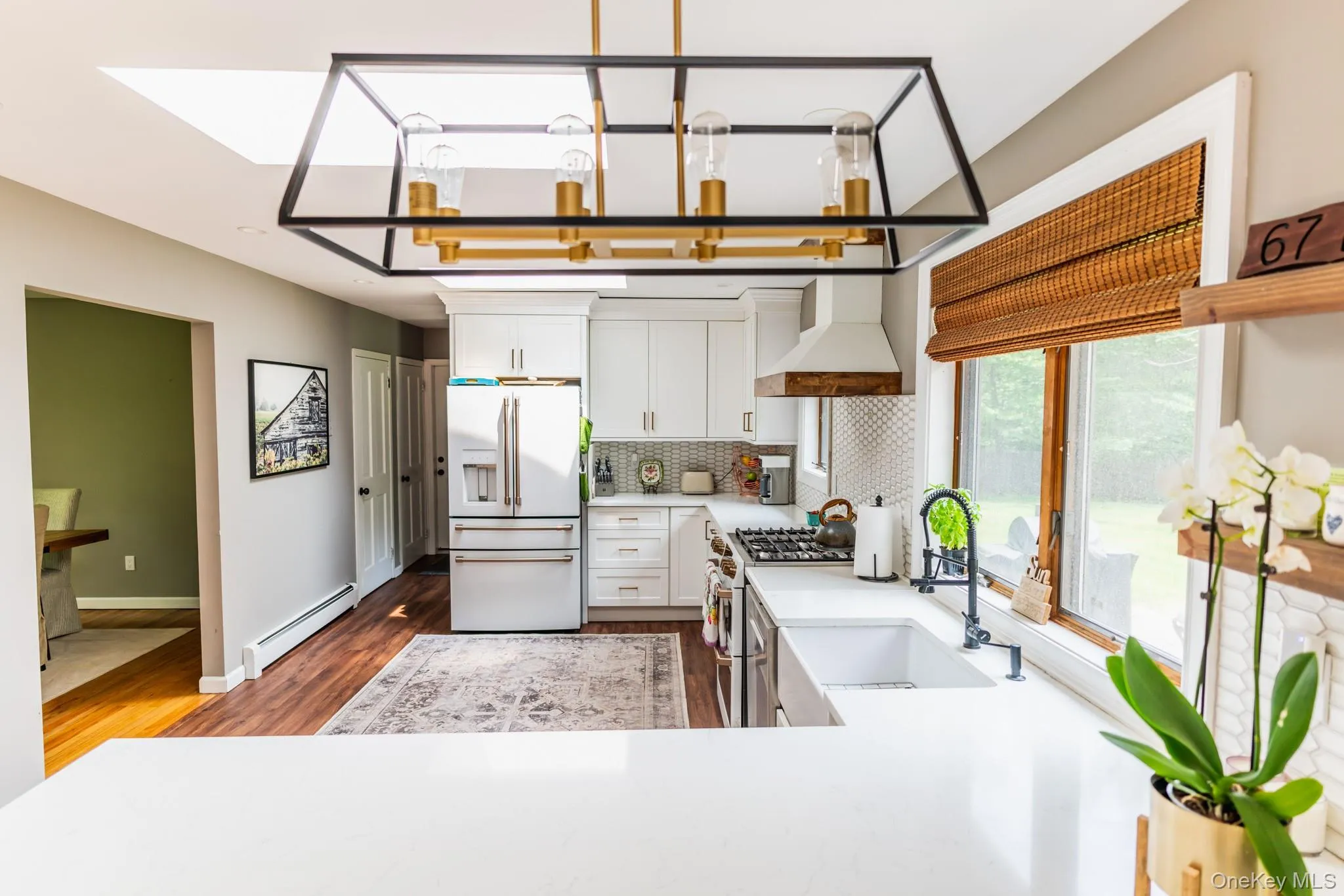 Kitchen featuring white appliances, custom range hood, baseboard heating, dark wood finished floors, and decorative backsplash Kitchen featuring white appliances, custom range hood, baseboard heating, dark wood finished floors, and decorative backsplash