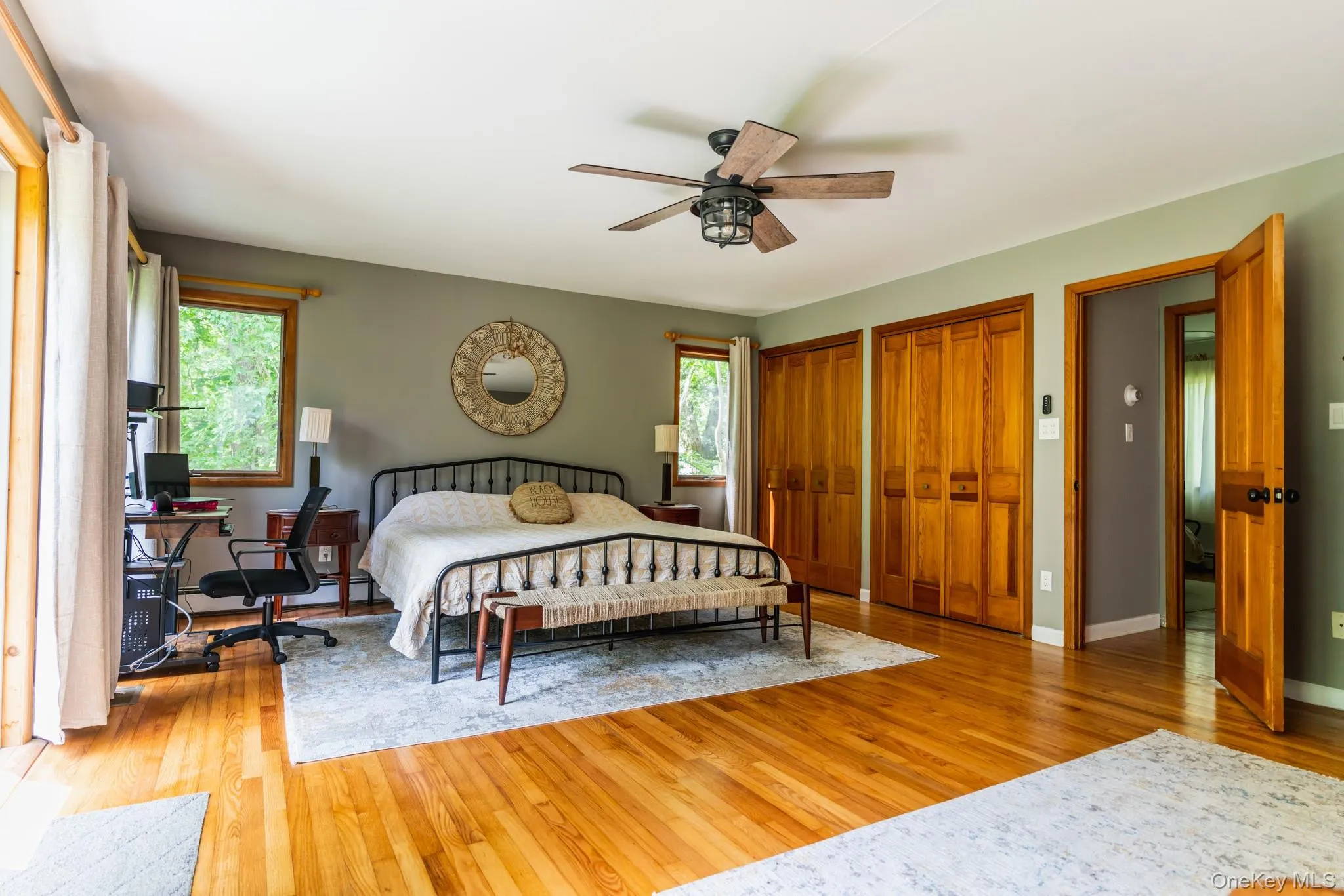 Bedroom with multiple closets, a desk, light wood finished floors, and ceiling fan Bedroom with multiple closets, a desk, light wood finished floors, and ceiling fan