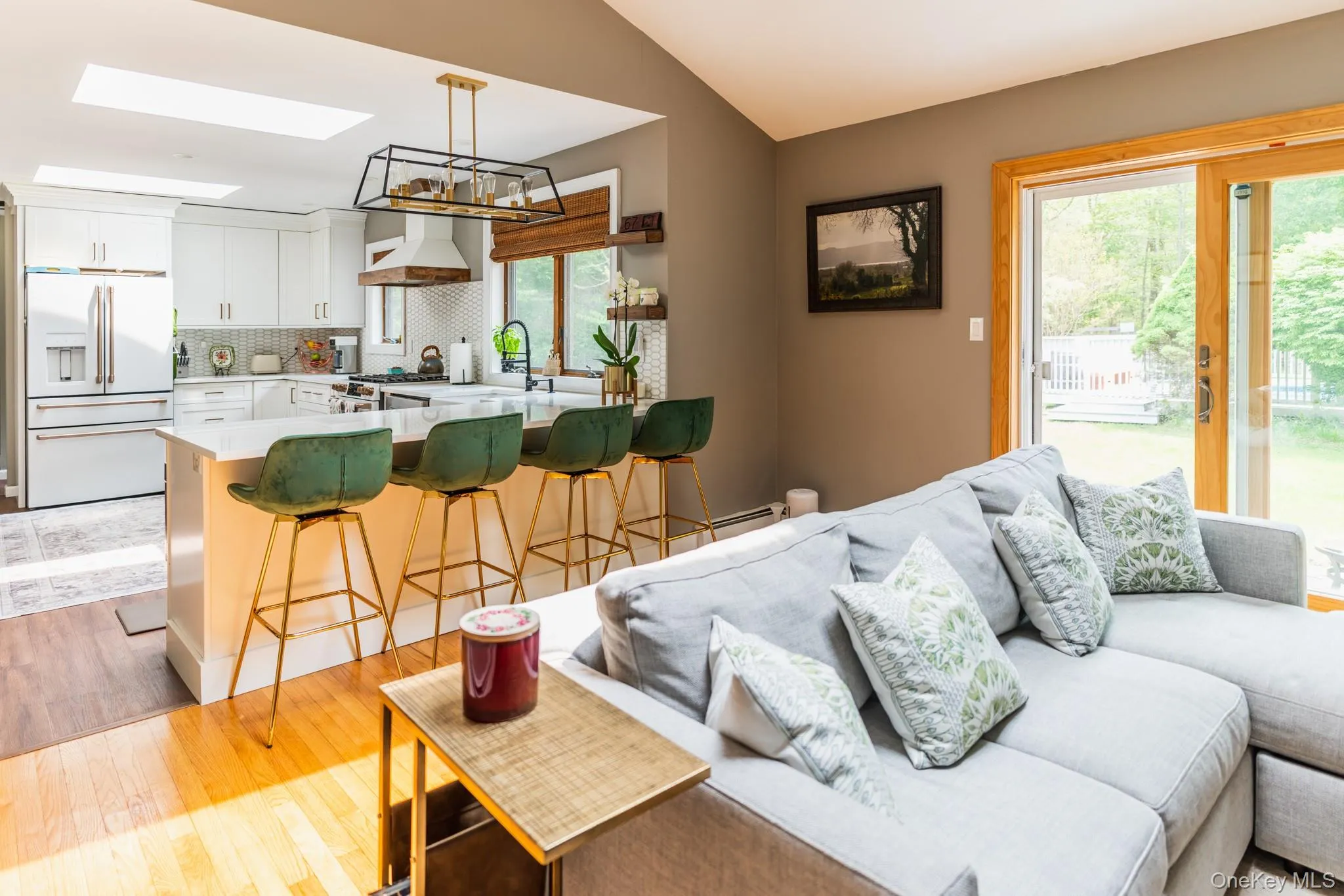 Living area with light wood-type flooring, a skylight, lofted ceiling, and a chandelier Living area with light wood-type flooring, a skylight, lofted ceiling, and a chandelier