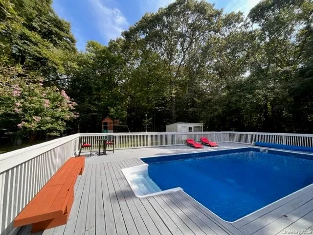 View of pool with an outbuilding, a deck, and view of wooded area View of pool with an outbuilding, a deck, and view of wooded area