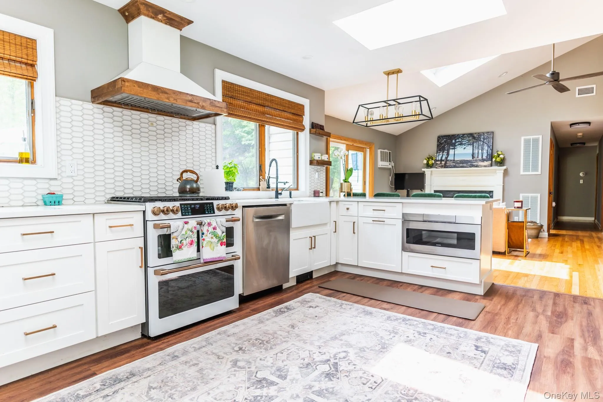 Kitchen featuring white cabinetry, stainless steel appliances, a skylight, a peninsula, and vaulted ceiling Kitchen featuring white cabinetry, stainless steel appliances, a skylight, a peninsula, and vaulted ceiling