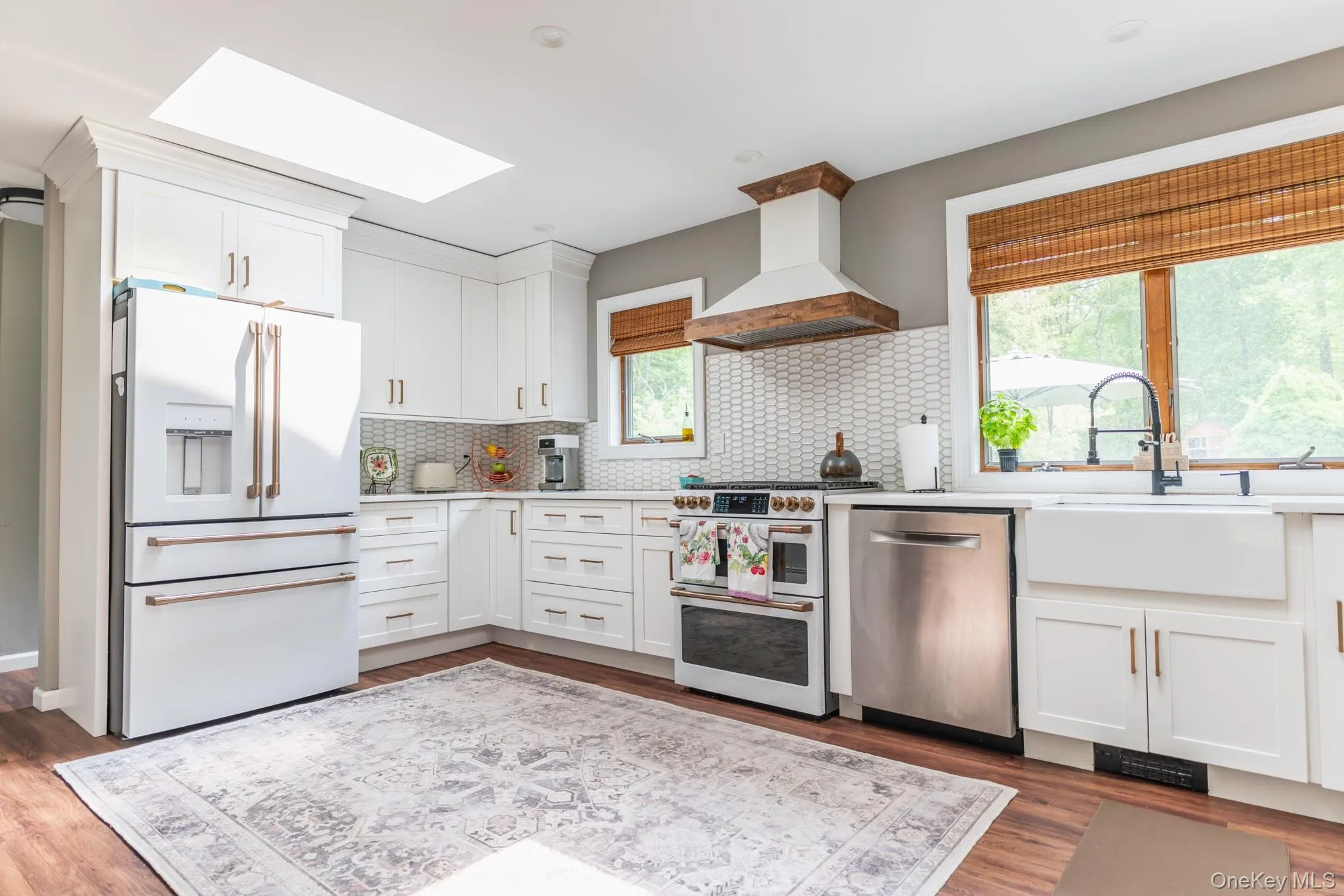 Kitchen featuring white appliances, a skylight, white cabinets, dark wood finished floors, and decorative backsplash Kitchen featuring white appliances, a skylight, white cabinets, dark wood finished floors, and decorative backsplash
