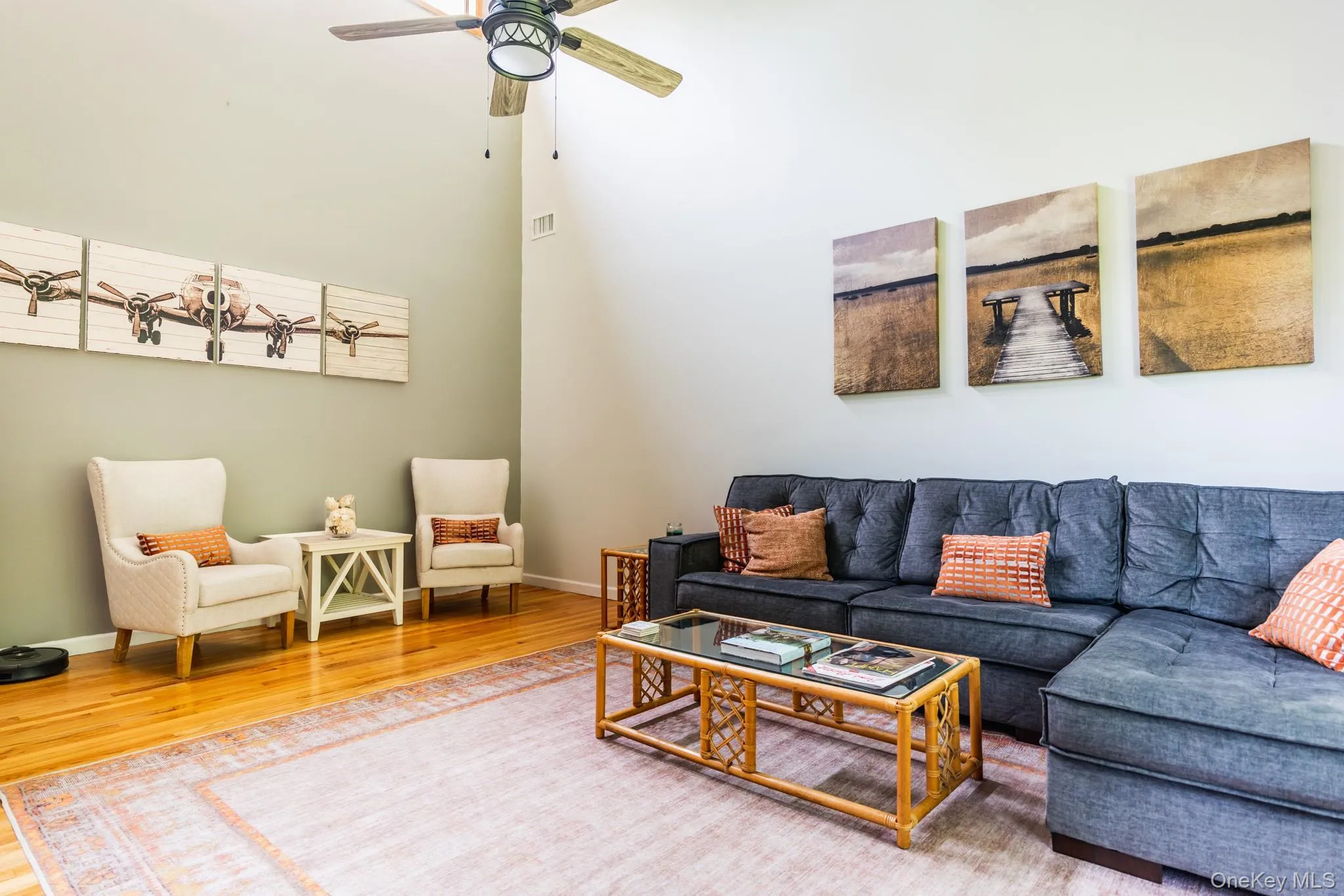 Living area featuring wood finished floors, a high ceiling, and ceiling fan Living area featuring wood finished floors, a high ceiling, and ceiling fan