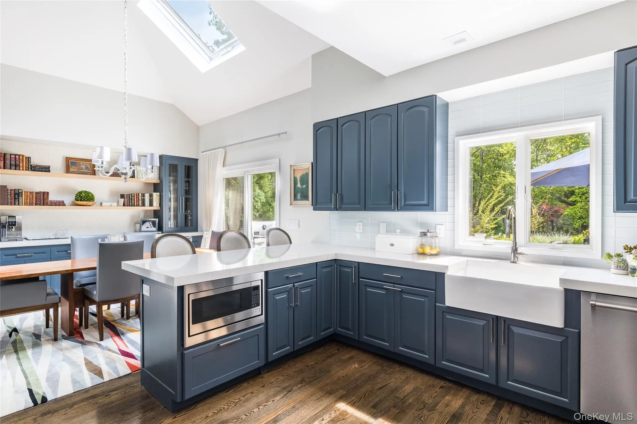 Kitchen with blue cabinets, lofted ceiling, a peninsula, and dark wood-style floors Kitchen with blue cabinets, lofted ceiling, a peninsula, and dark wood-style floors