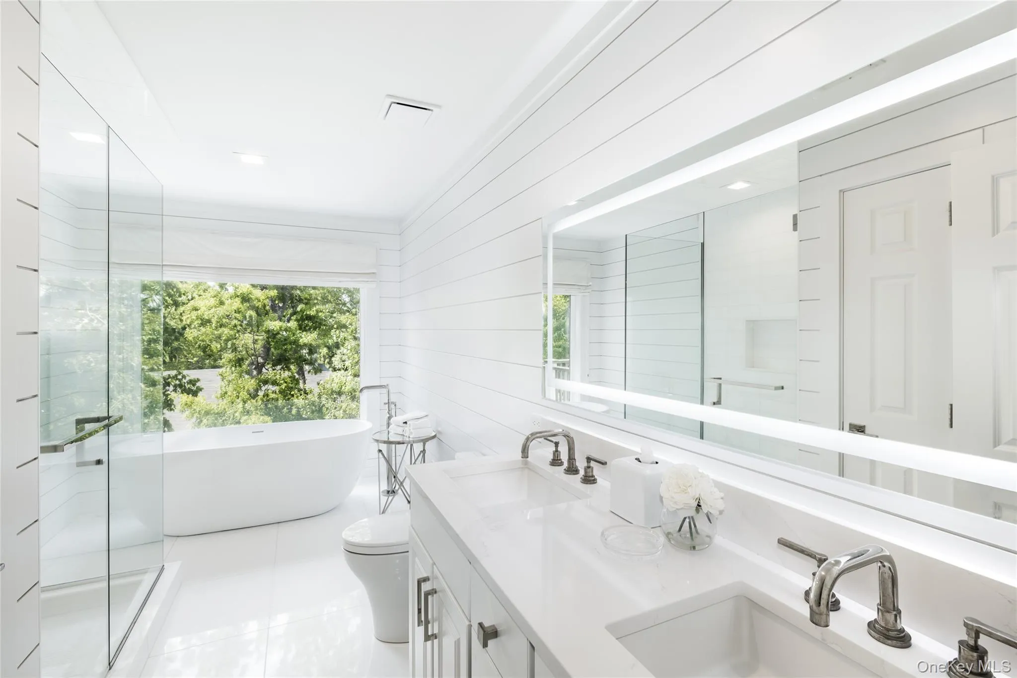Bathroom with healthy amount of natural light, a freestanding tub, double vanity, wood walls, and a stall shower Bathroom with healthy amount of natural light, a freestanding tub, double vanity, wood walls, and a stall shower