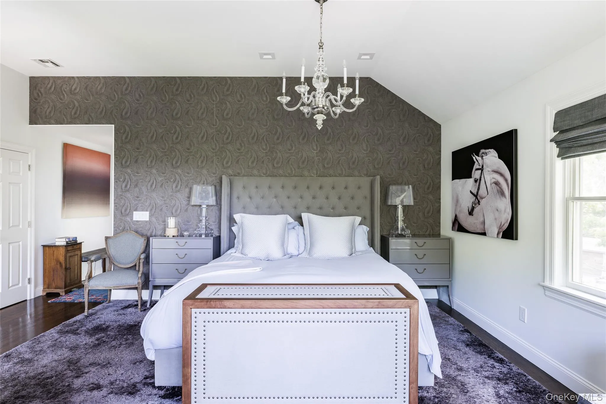 Bedroom featuring an accent wall, wallpapered walls, a chandelier, lofted ceiling, and dark wood-style floors Bedroom featuring an accent wall, wallpapered walls, a chandelier, lofted ceiling, and dark wood-style floors