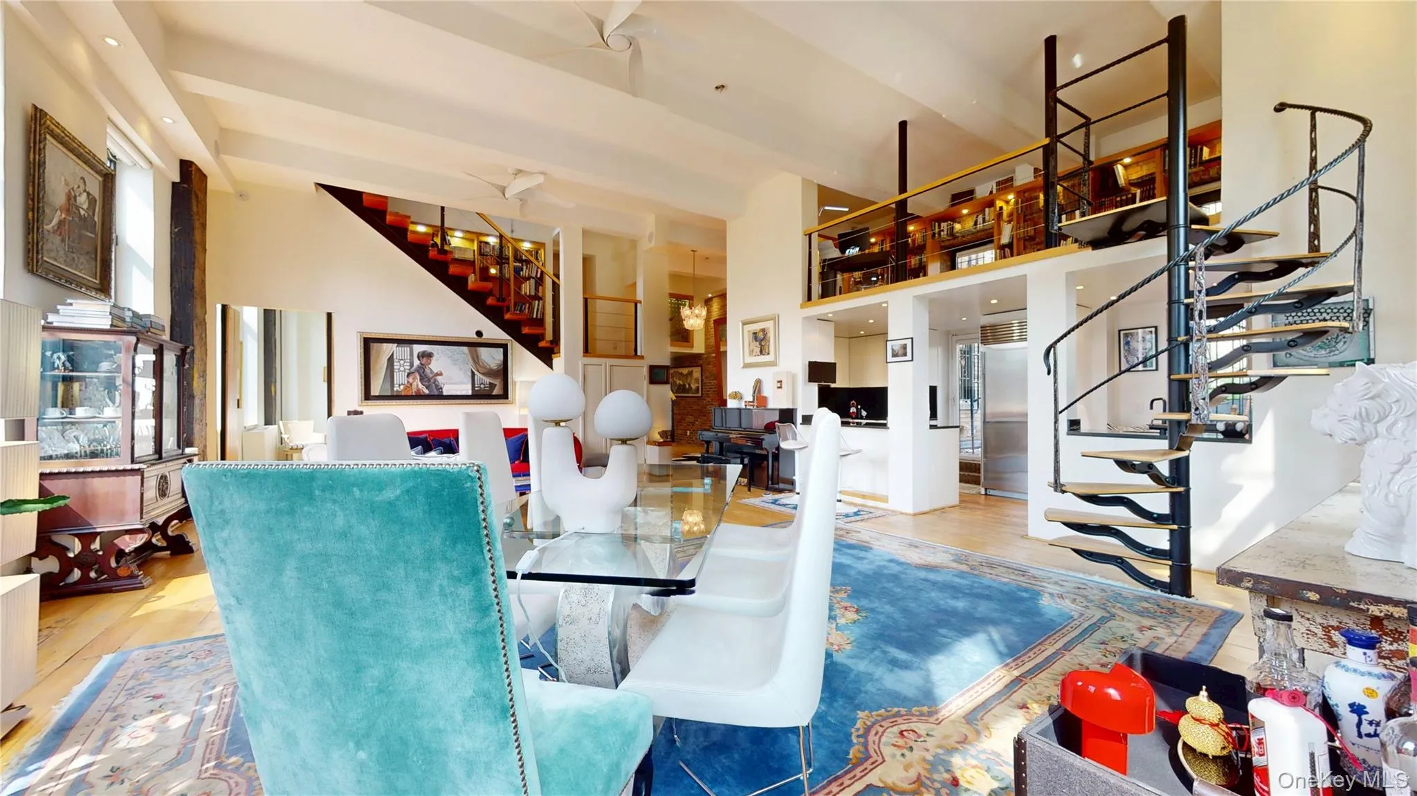 Dining space featuring stairs, wood finished floors, and a towering ceiling Dining space featuring stairs, wood finished floors, and a towering ceiling