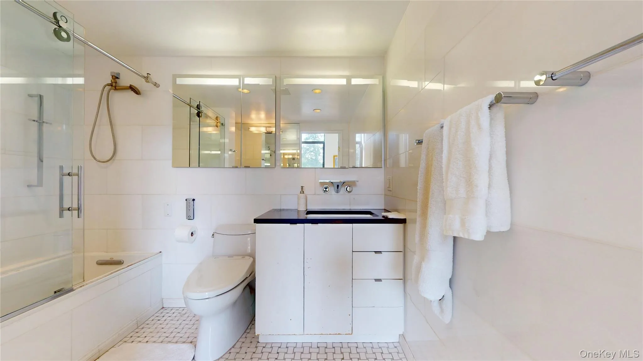 Full bath featuring shower / bath combination with glass door, tile walls, and vanity Full bath featuring shower / bath combination with glass door, tile walls, and vanity