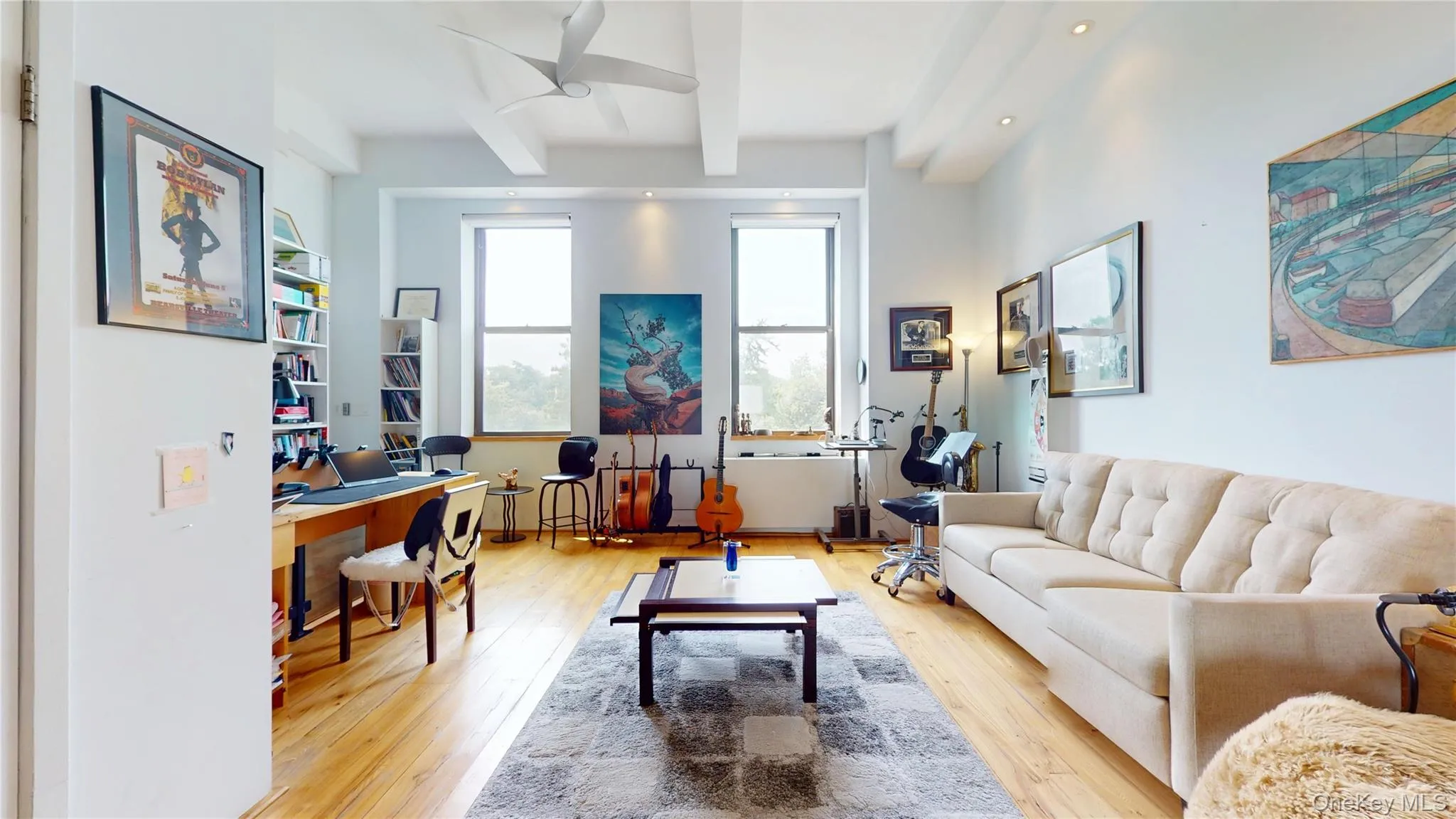 Living room featuring beam ceiling, a desk, light wood-style flooring, and a ceiling fan Living room featuring beam ceiling, a desk, light wood-style flooring, and a ceiling fan