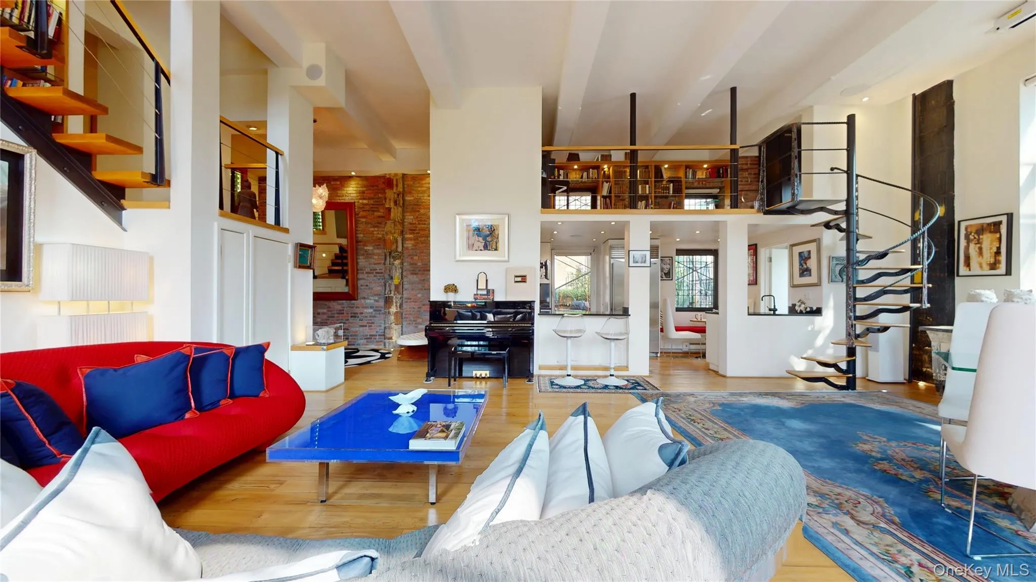 Living room with stairs, a high ceiling, wood finished floors, and brick wall Living room with stairs, a high ceiling, wood finished floors, and brick wall